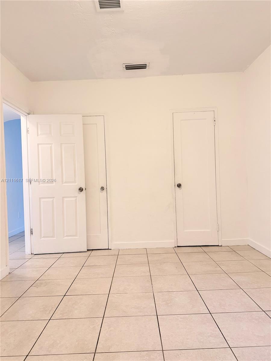Interior space featuring neutral wall tones, large-format ceramic tile flooring, and multiple solid-core panel doors