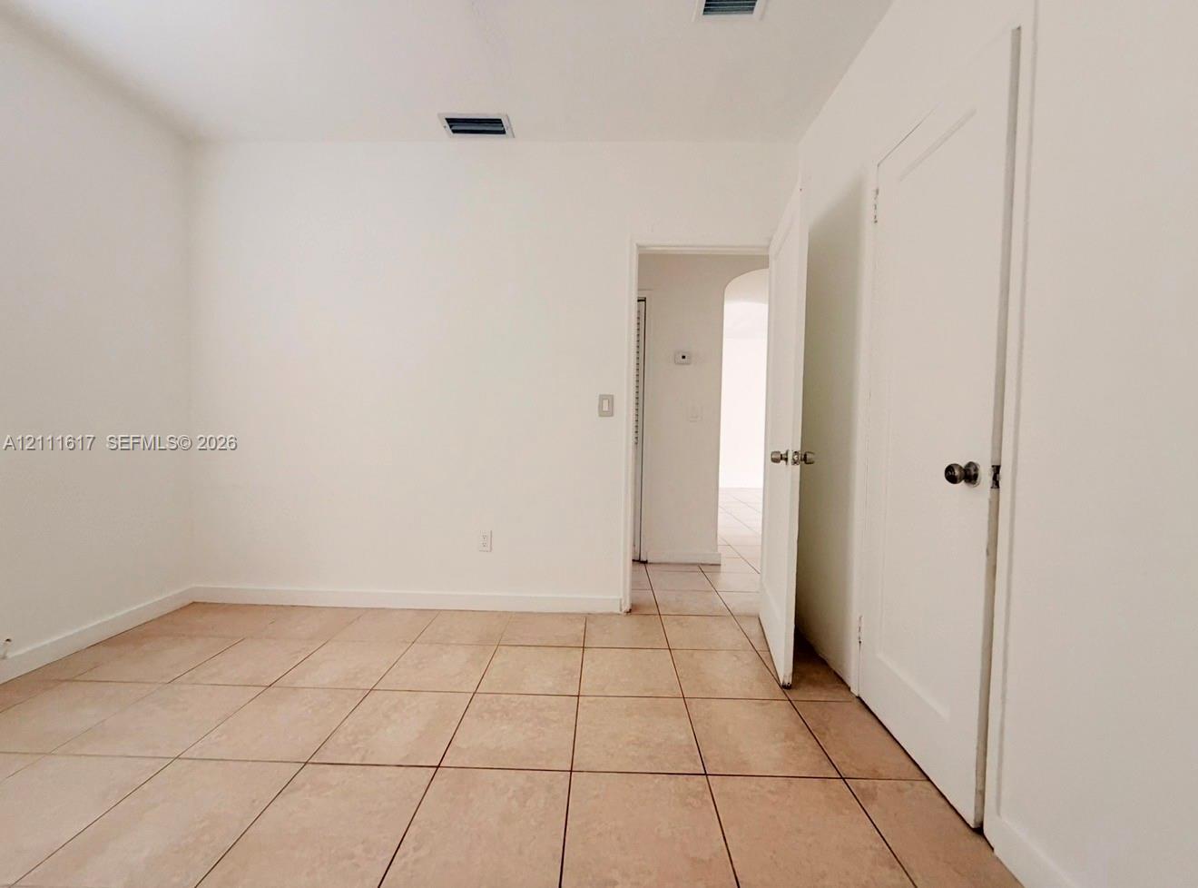 Neutral-toned tile flooring, solid-core interior doors with metallic hardware, and white-finished walls