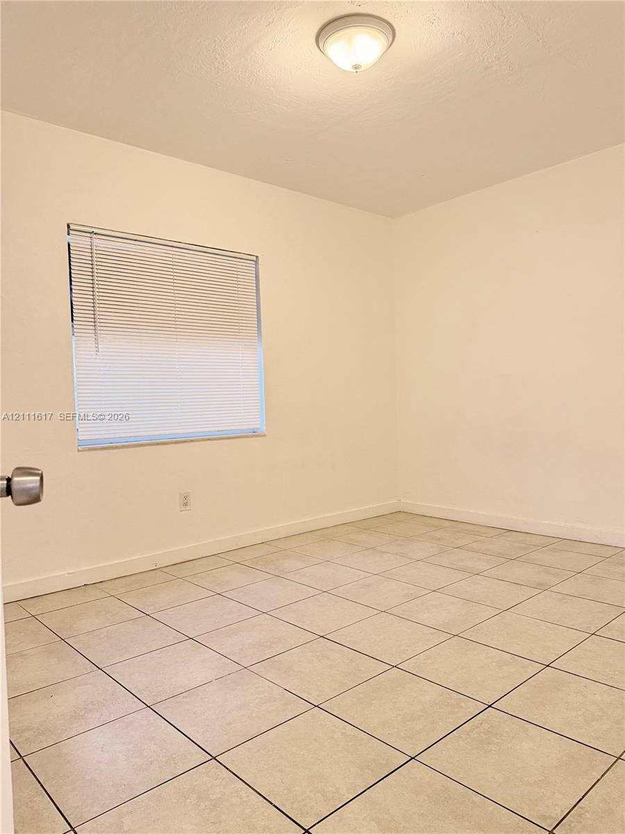 Neutral-toned tile flooring, flush-mount dome ceiling lighting, and horizontal window blinds