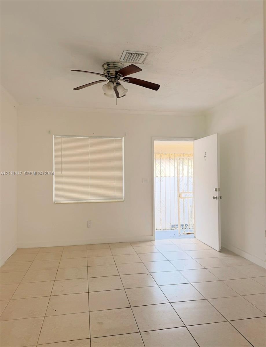 Neutral-toned tiled flooring, ceiling fan with integrated lighting, and window with attached horizontal blinds