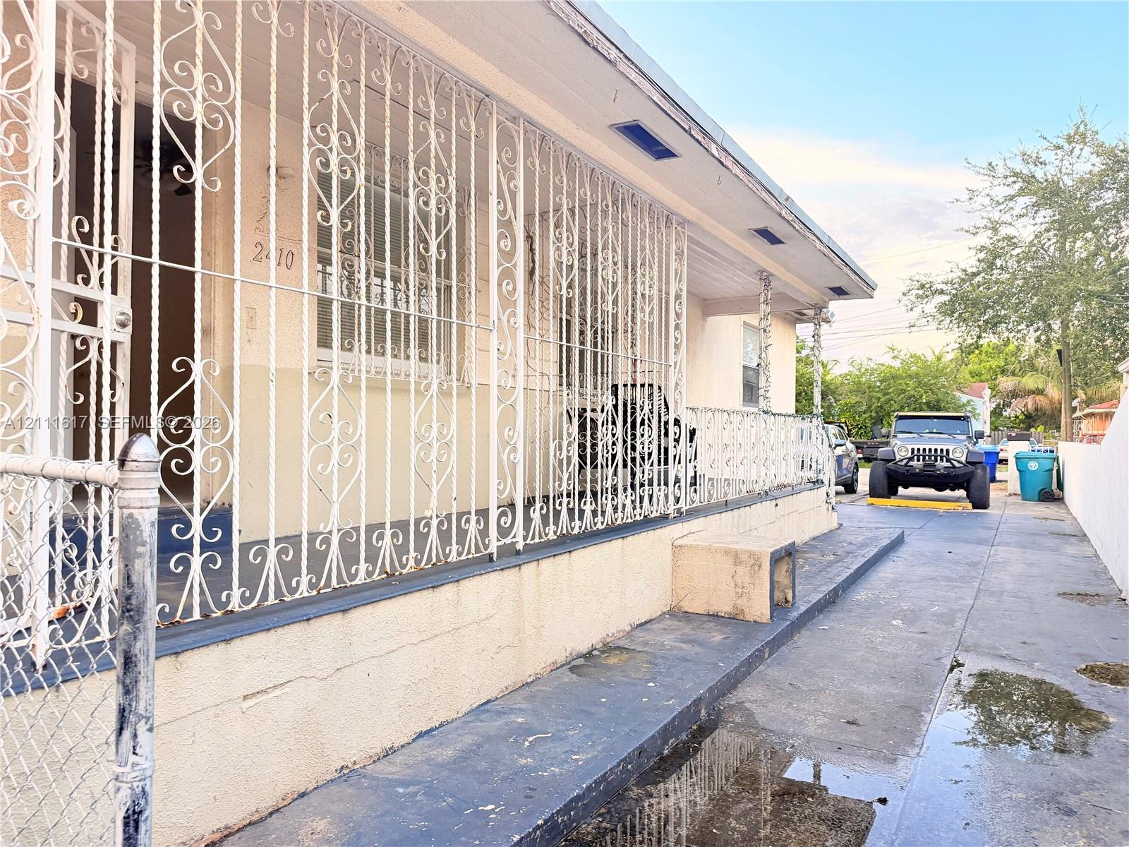 Exterior facade featuring decorative metal security grilles, covered porch area, and concrete driveway