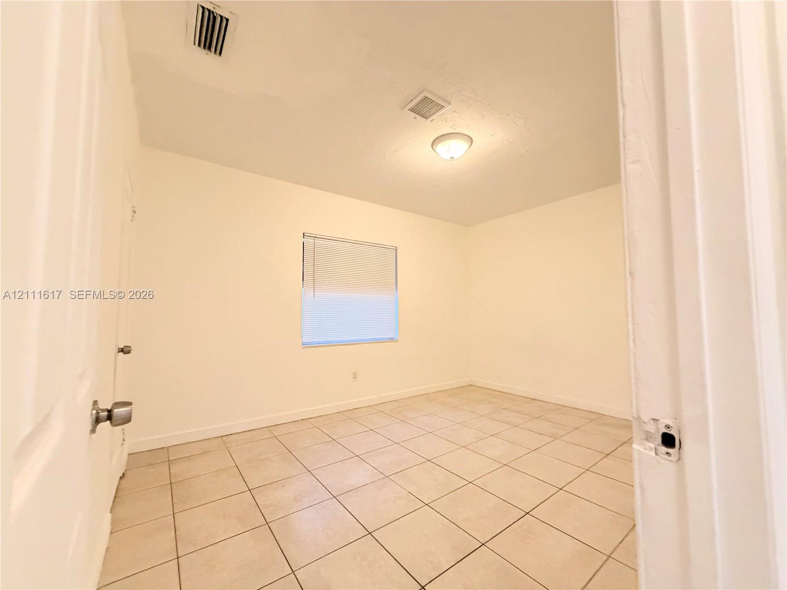 Room featuring neutral wall finishes, tile flooring, and a single window with integrated blinds