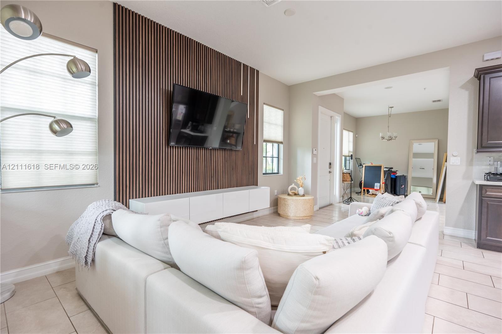 Vertical wood-slat accent wall featuring a white floating media console and light-toned tile flooring