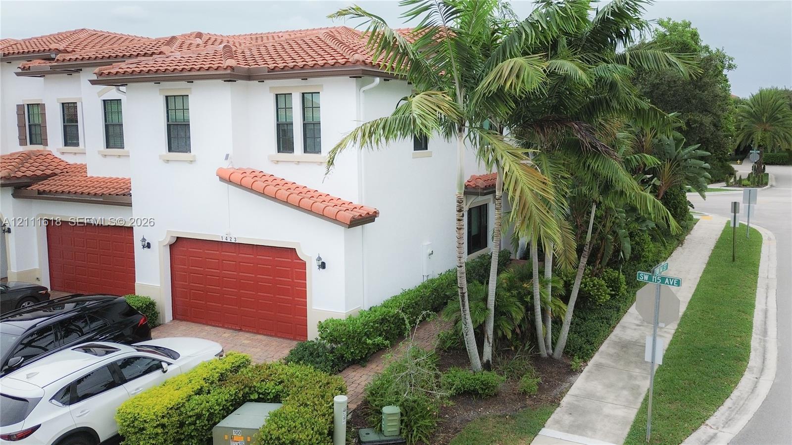 Mediterranean-style exterior featuring white stucco finish, red tile roofing, and prominent multi-car garage with articulated doors Mediterranean-style exterior featuring white stucco finish, red tile roofing, and prominent multi-car garage with articulated doors