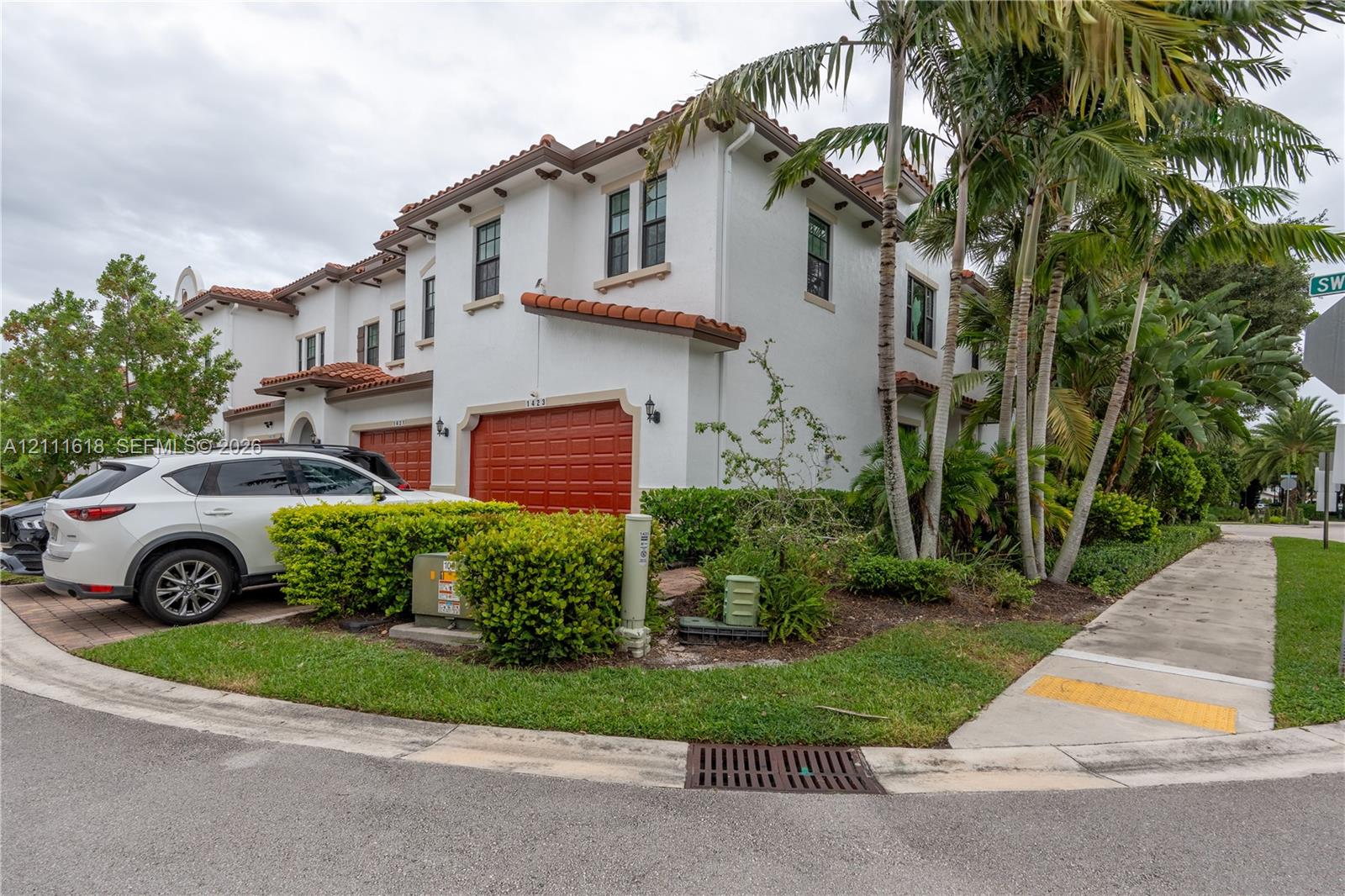 Mediterranean-style exterior featuring a white stucco facade, multi-level terracotta tile roofing, and arched garage entryways