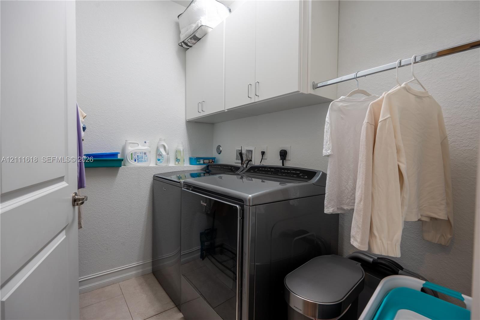 Laundry area featuring white built-in upper cabinetry, tile flooring, and a metal clothing rod