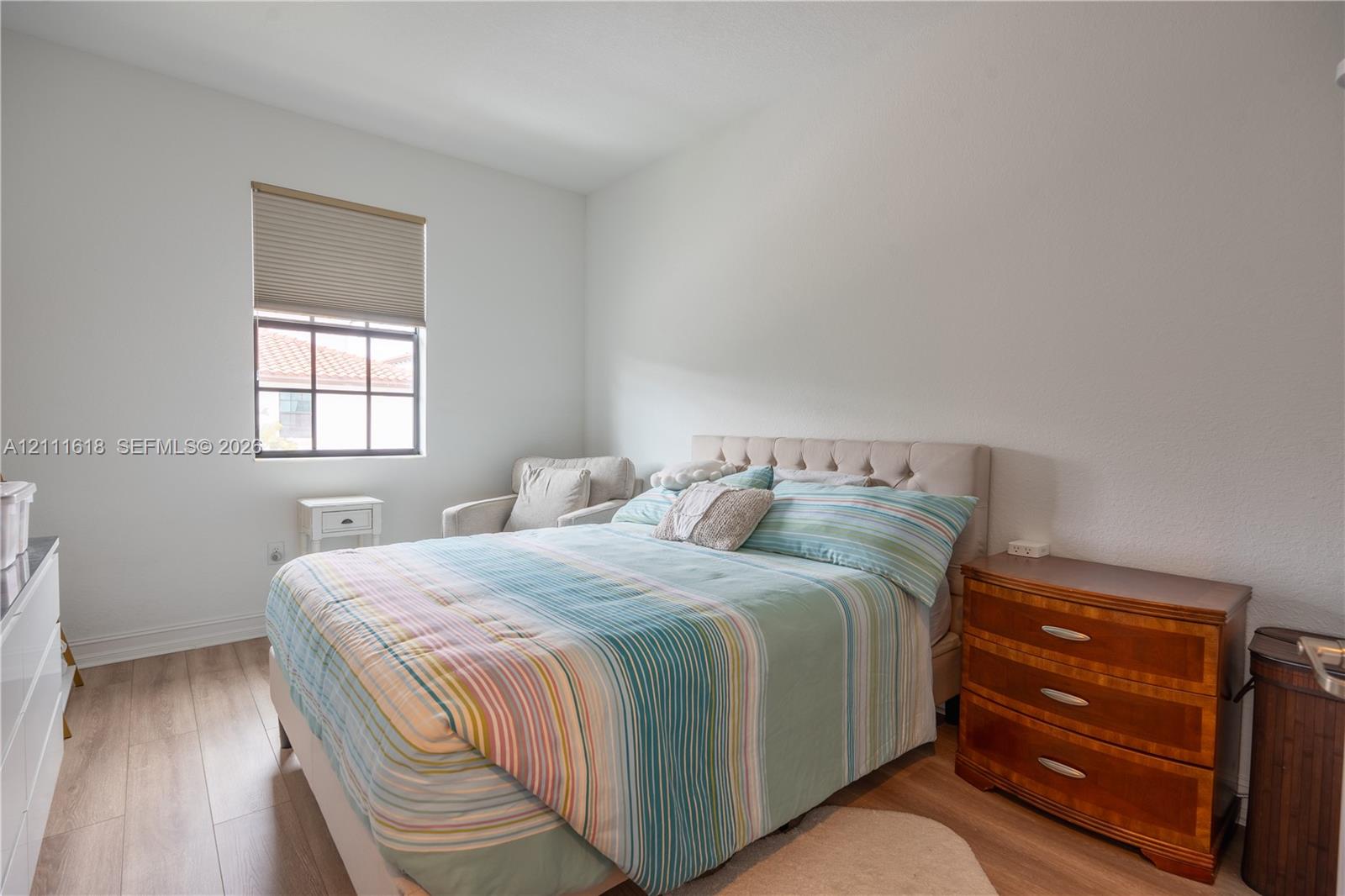 Wood-finish flooring, multi-pane window with top-down cellular shade, and neutral wall tones