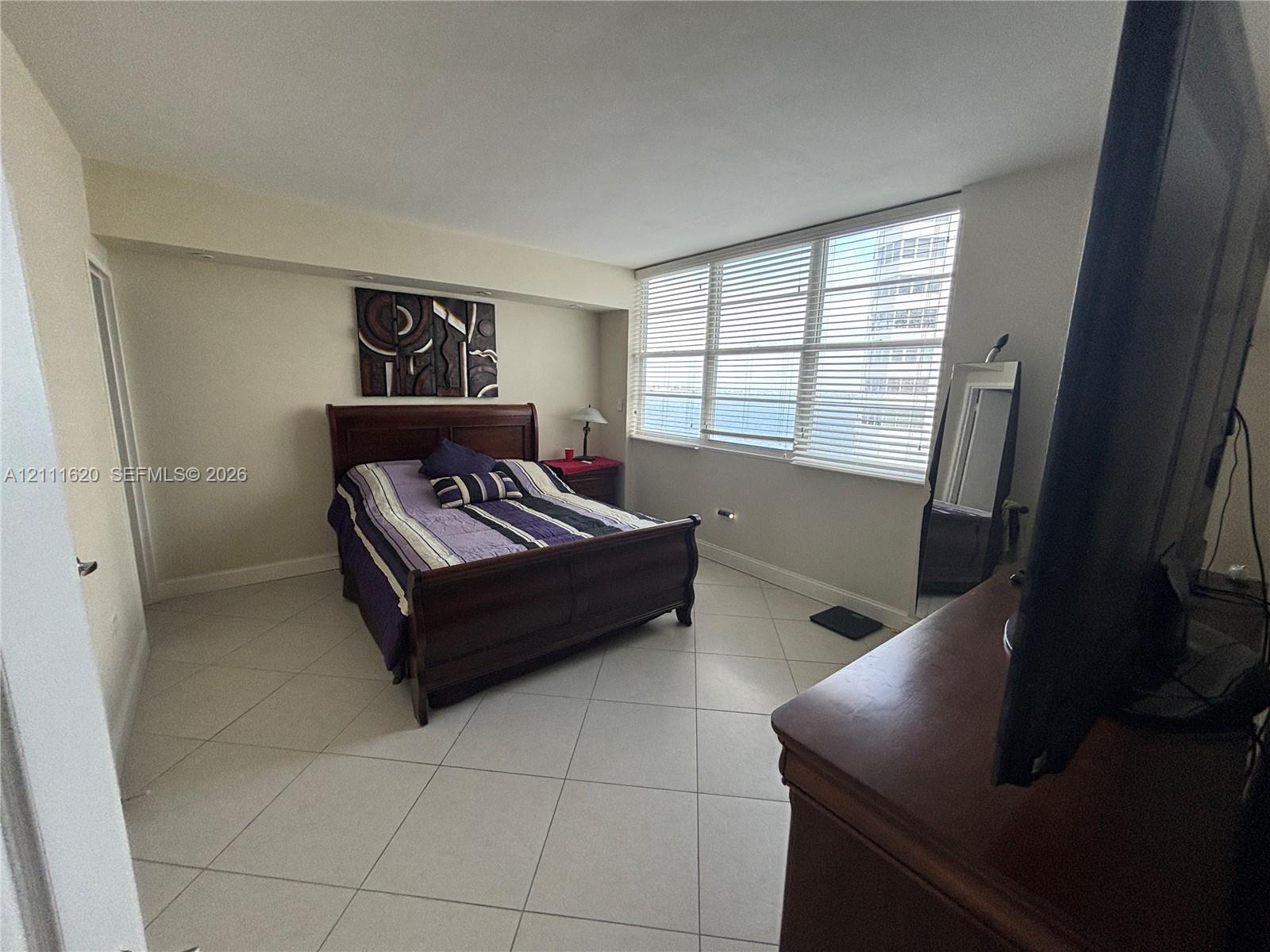 Light-filled room featuring neutral tile flooring, expansive multi-pane windows, and horizontal blinds