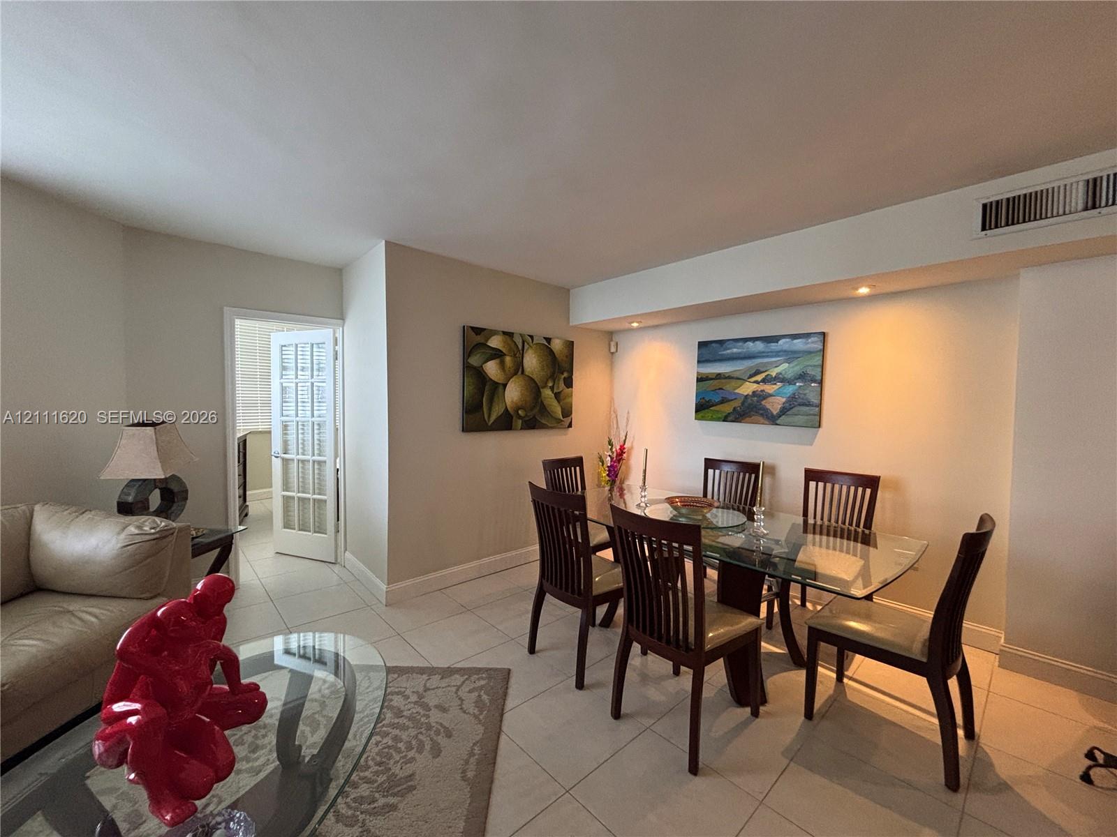 Open-concept interior featuring light-colored tile flooring, recessed ceiling lighting, and a French door with glass panels