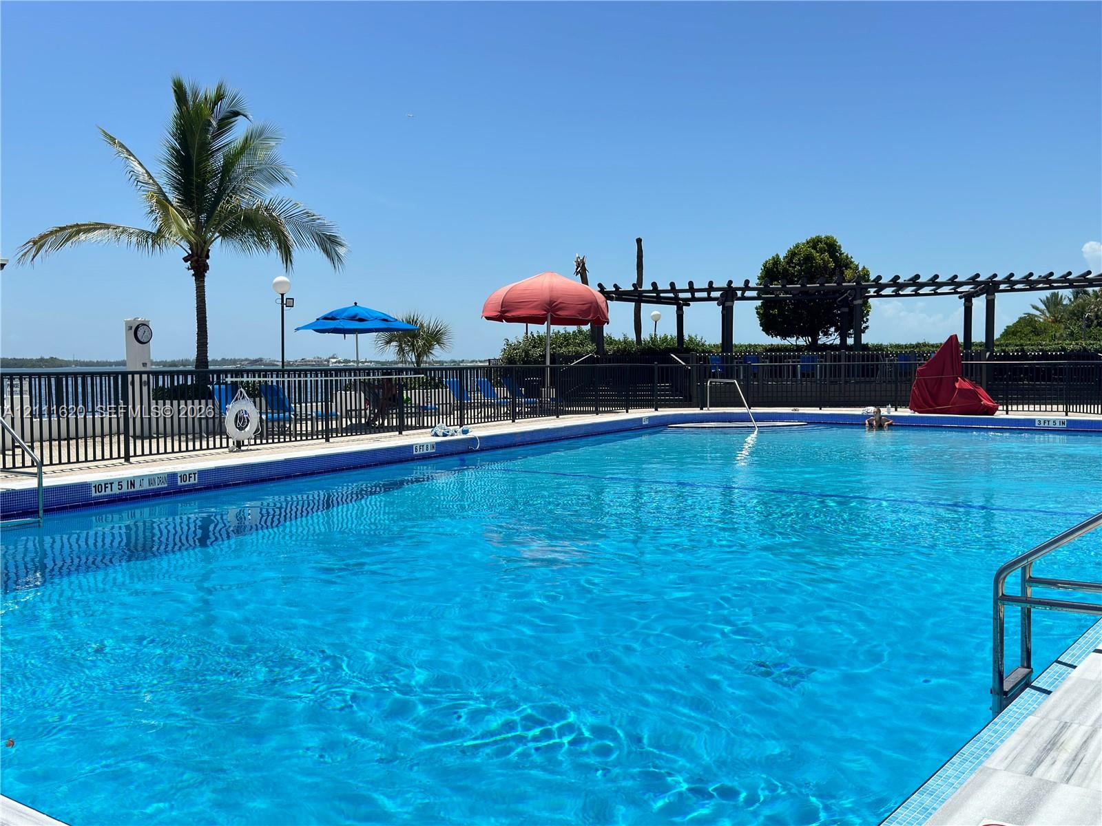 Swimming pool featuring a metal perimeter fence, a pergola, and water access