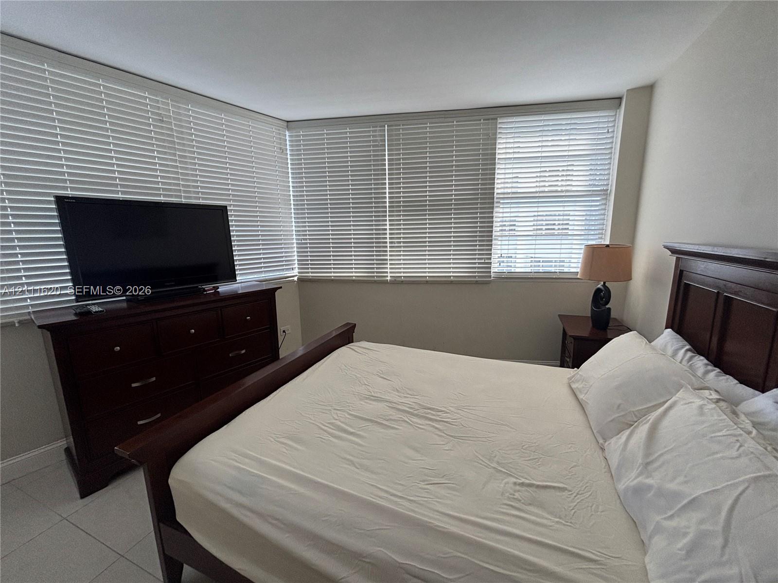 Large windows featuring horizontal blinds and neutral-tone tile flooring