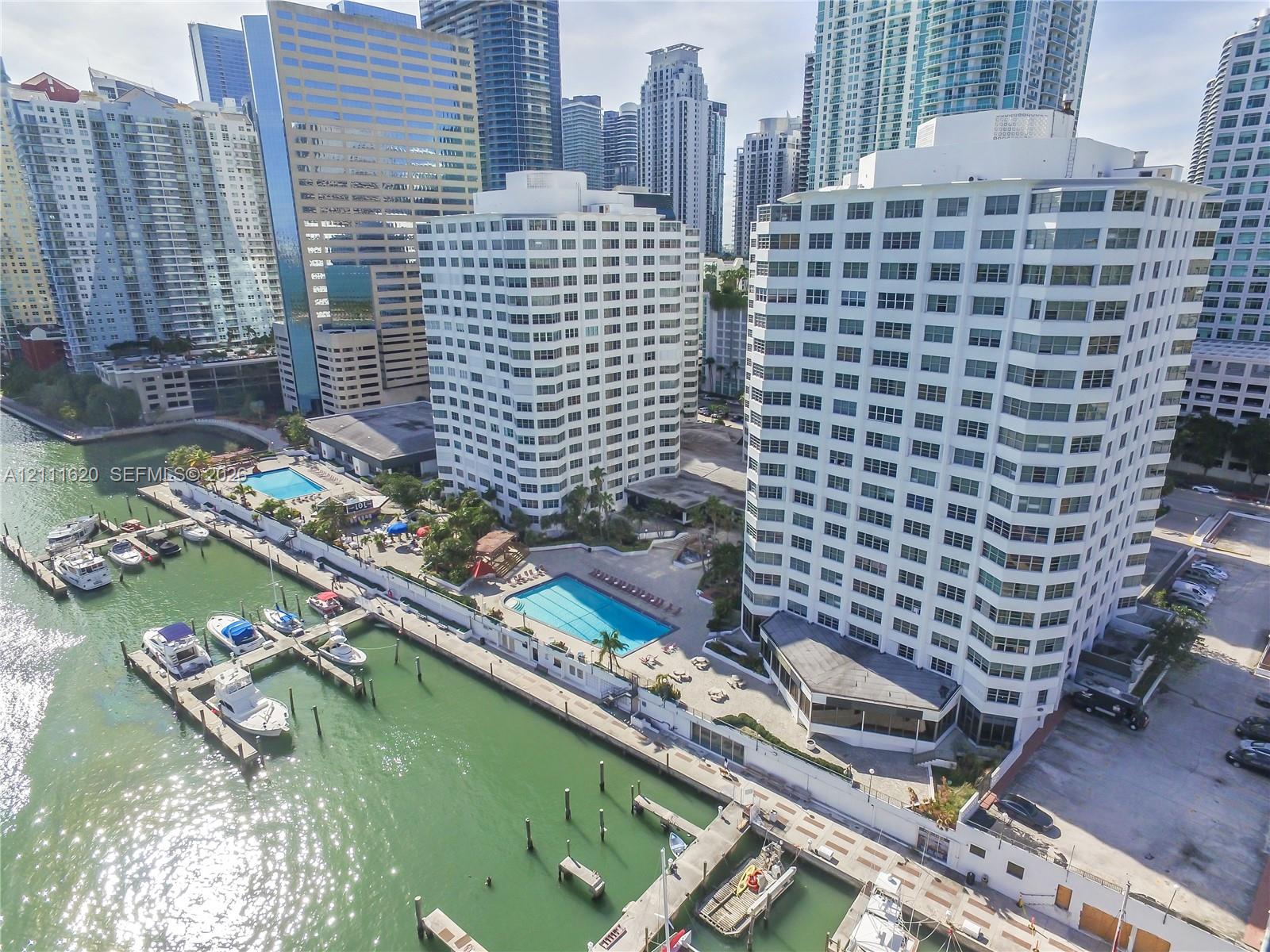 High-rise waterfront property featuring a deep-water dock, multiple swimming pools, and paved sunning decks