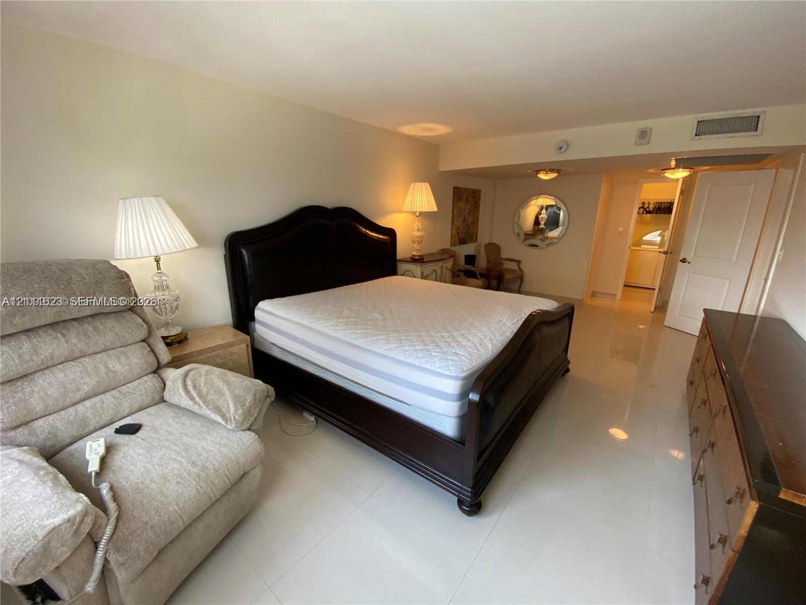 Neutral-toned interior space featuring polished tile flooring, recessed ceiling lighting, and a circular wall mirror