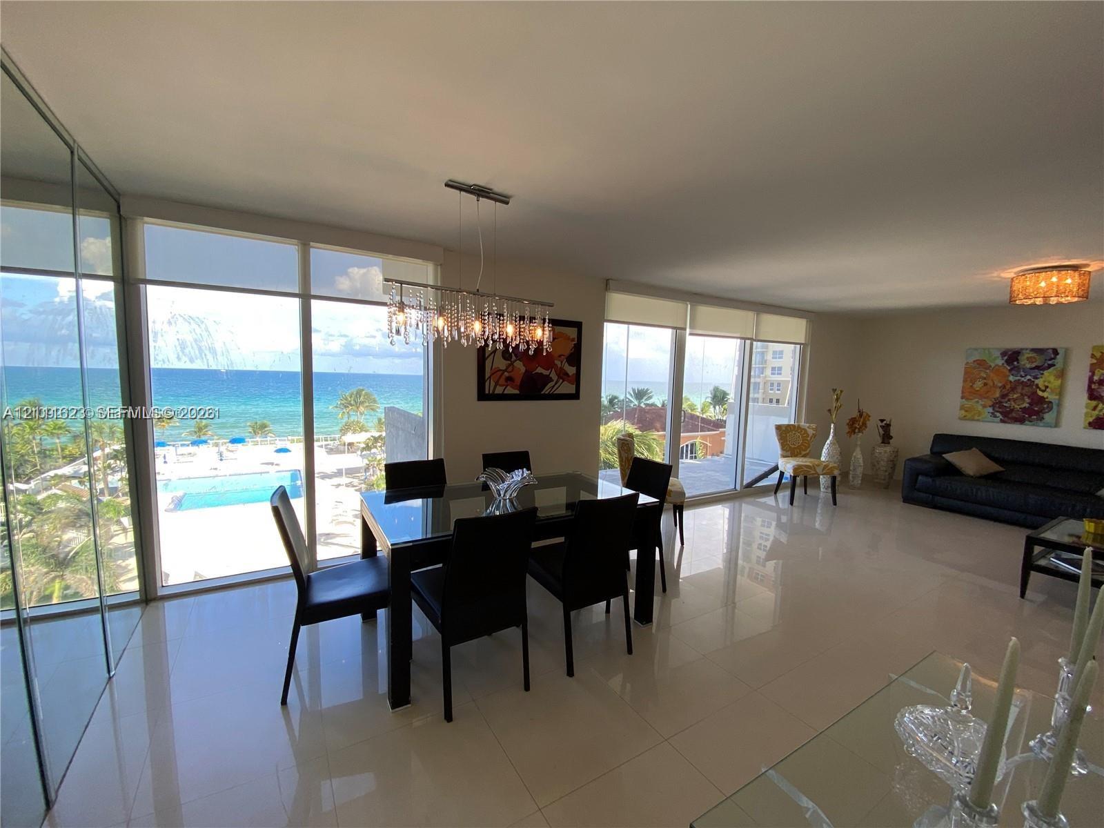 Floor-to-ceiling glass windows, polished tile flooring, crystal chandelier, and integrated mirrored wall paneling