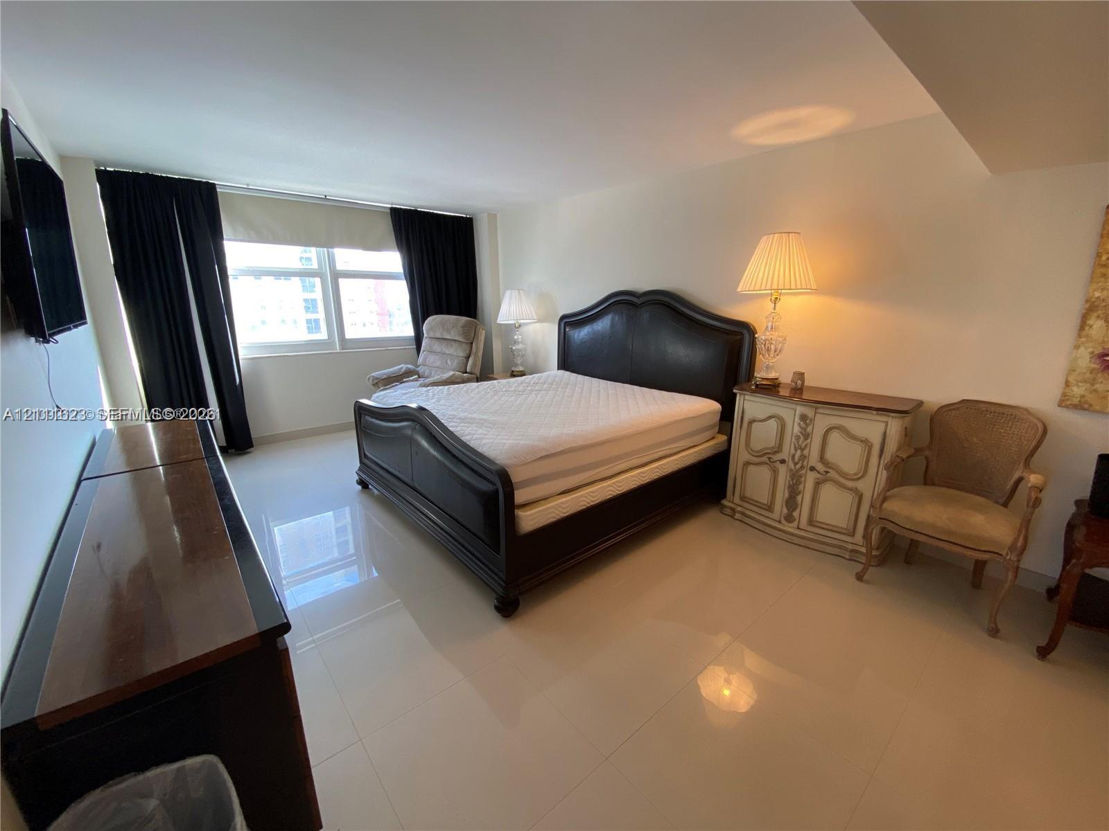Large bedroom featuring neutral tile flooring, expansive window, and recessed lighting