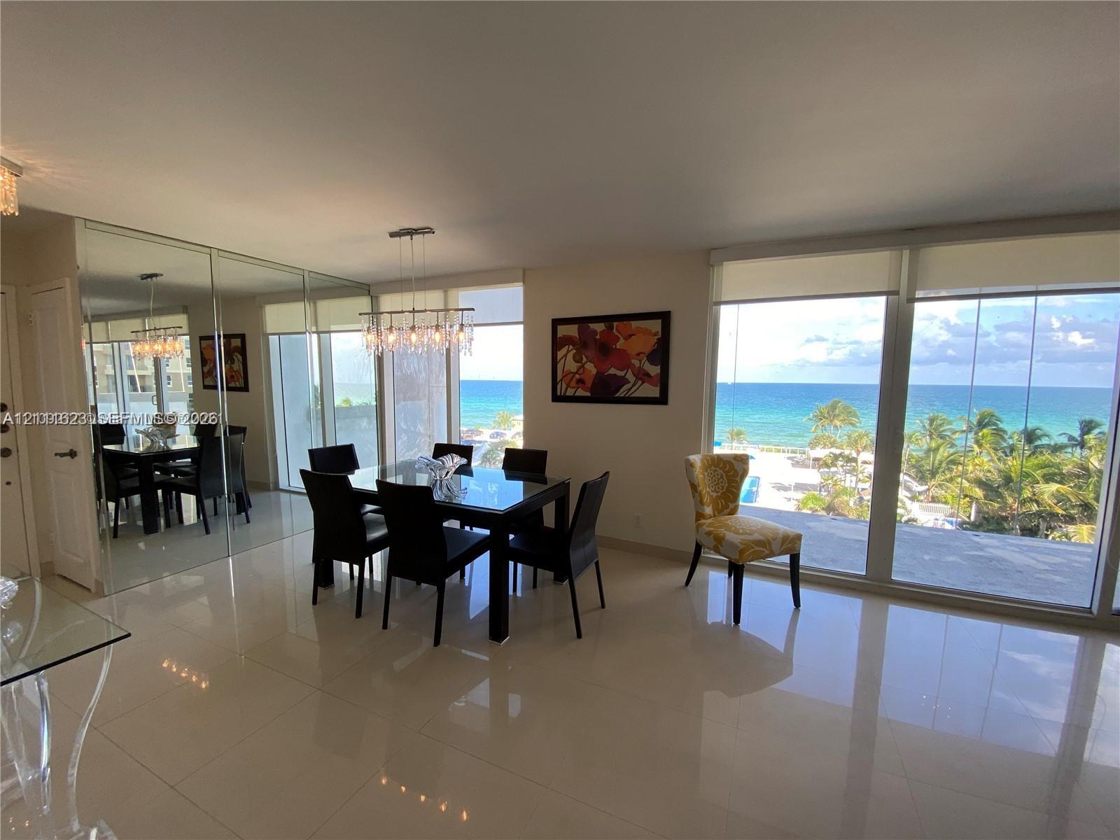 Large-format tile flooring, wall-to-wall mirrored panels, multi-pane floor-to-ceiling windows, and contemporary multi-bulb chandelier