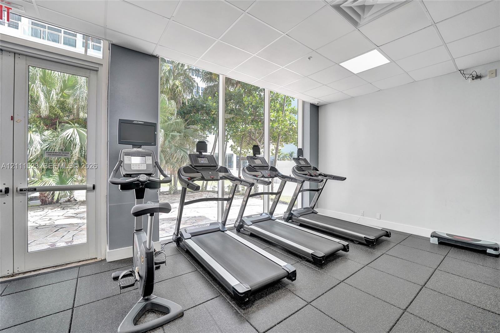 Fitness center featuring floor-to-ceiling windows, rubberized modular flooring, and recessed ceiling lighting