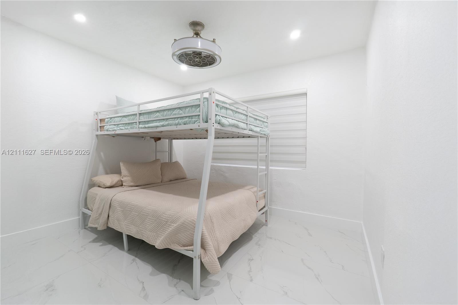 Large-format tile flooring, recessed ceiling lighting, and a circular drum-style ceiling fan with an integrated light fixture