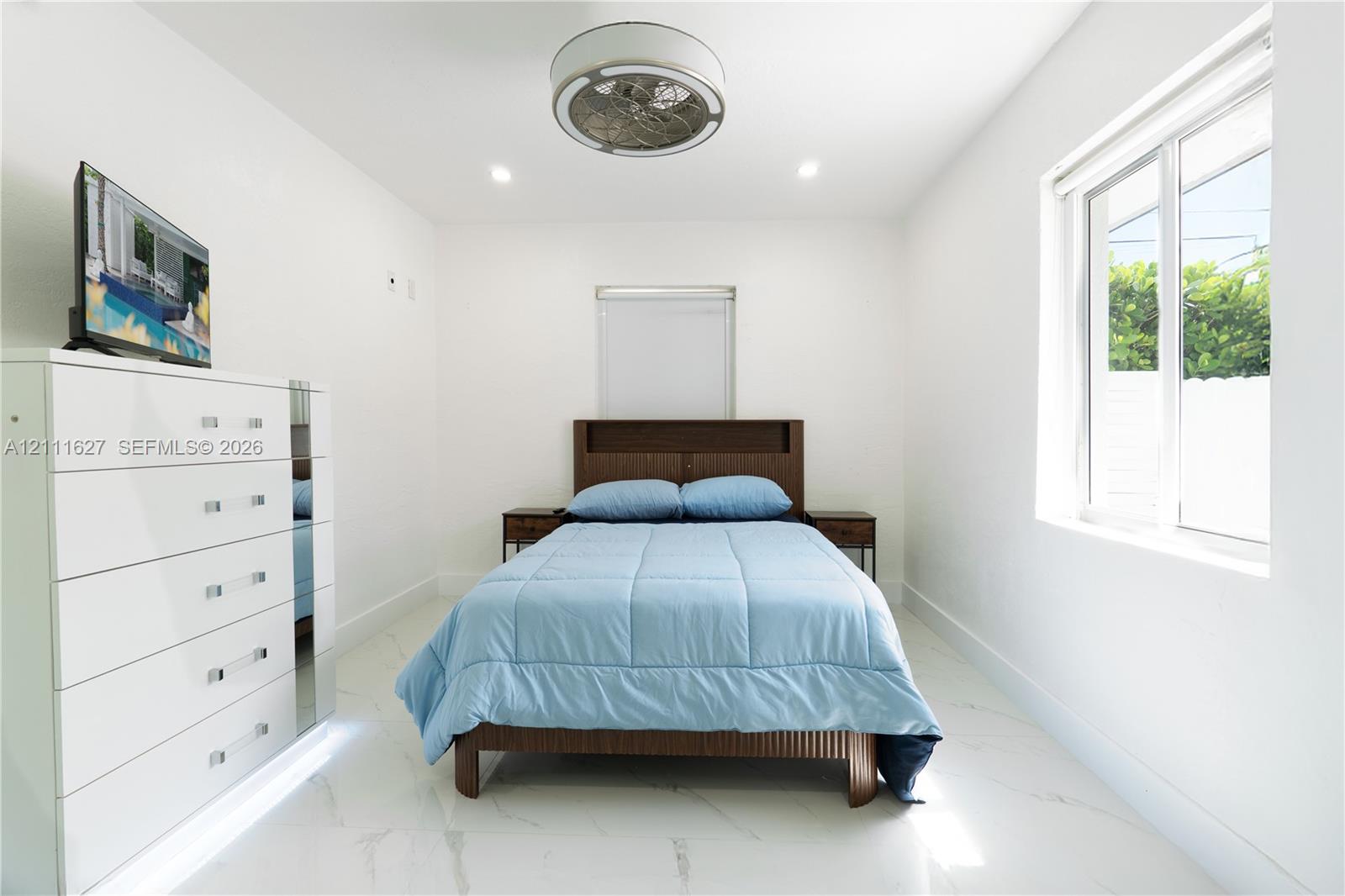 Interior space featuring polished white tile flooring, recessed lighting, and a contemporary circular flush-mount ceiling fan