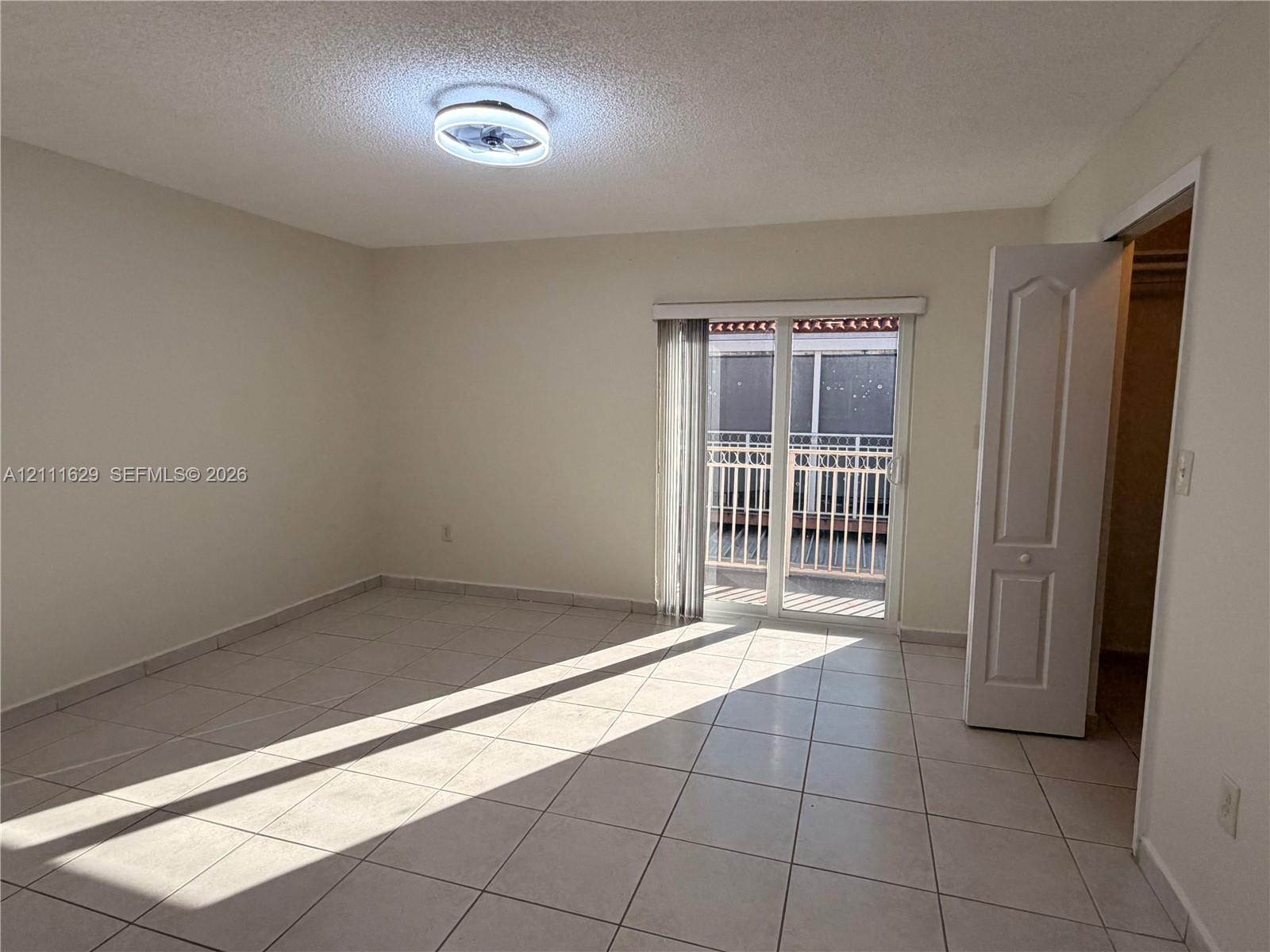 Ceramic tile flooring, flush-mount ceiling light fixture, sliding glass door, and a built-in closet with a panel door