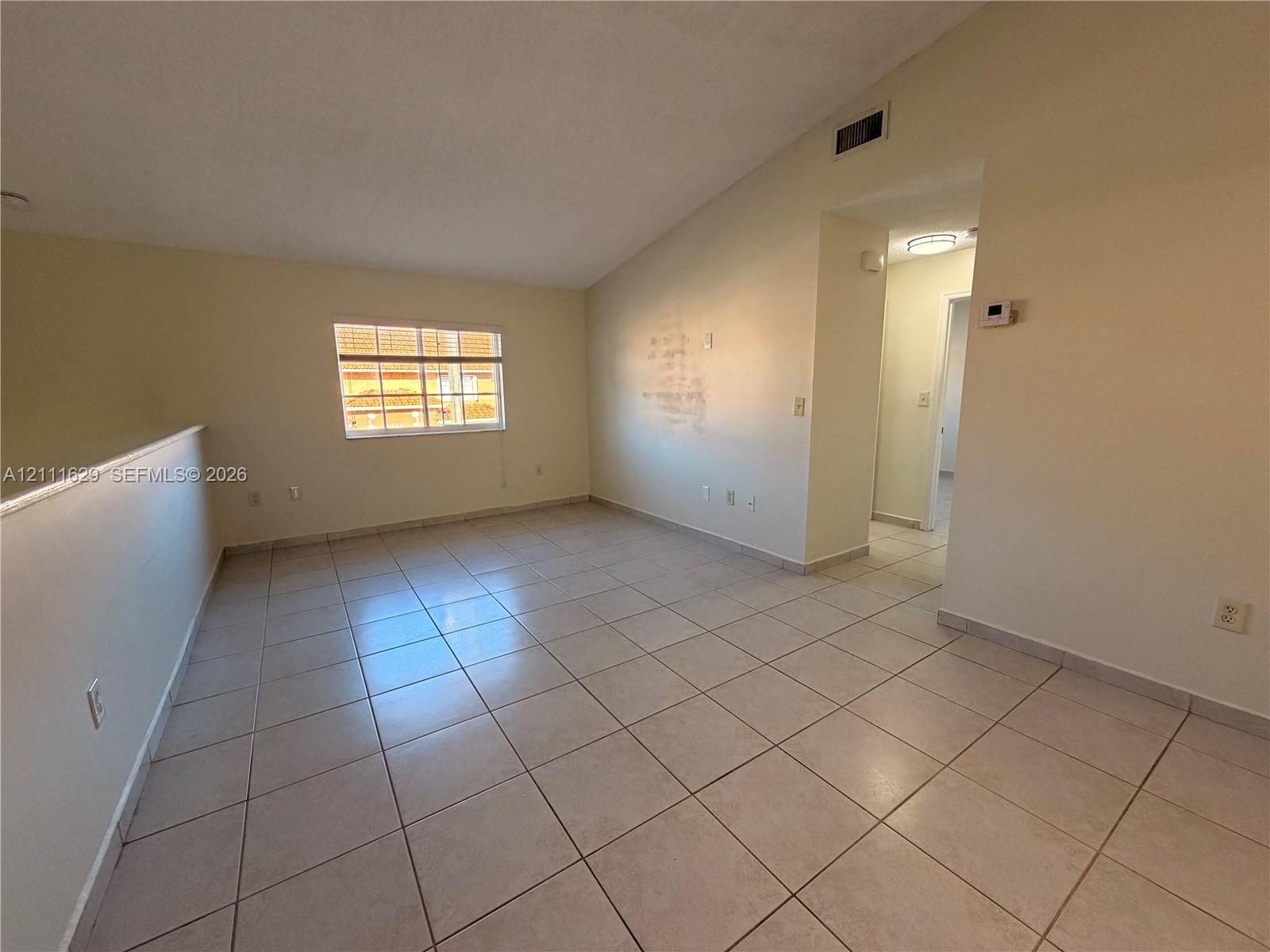 Vaulted ceiling, ceramic tile flooring, and a recessed window with horizontal grid detailing
