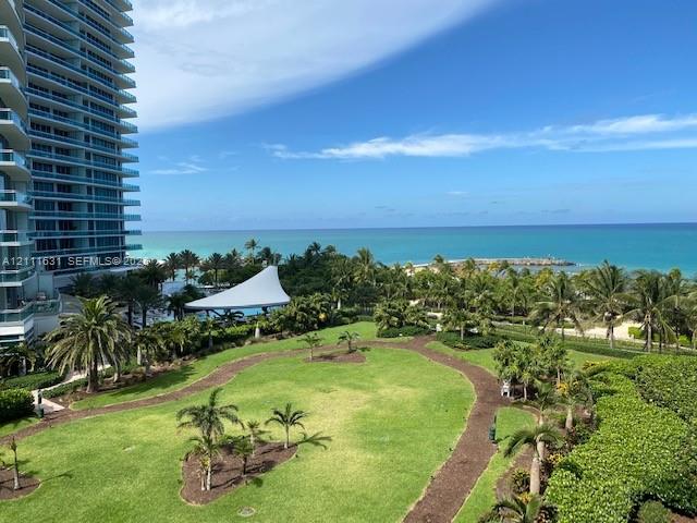 Expansive grounds featuring manicured lawns, winding landscape pathways, mature palm trees, and an open-air pavilion, set against an ocean backdrop Expansive grounds featuring manicured lawns, winding landscape pathways, mature palm trees, and an open-air pavilion, set against an ocean backdrop