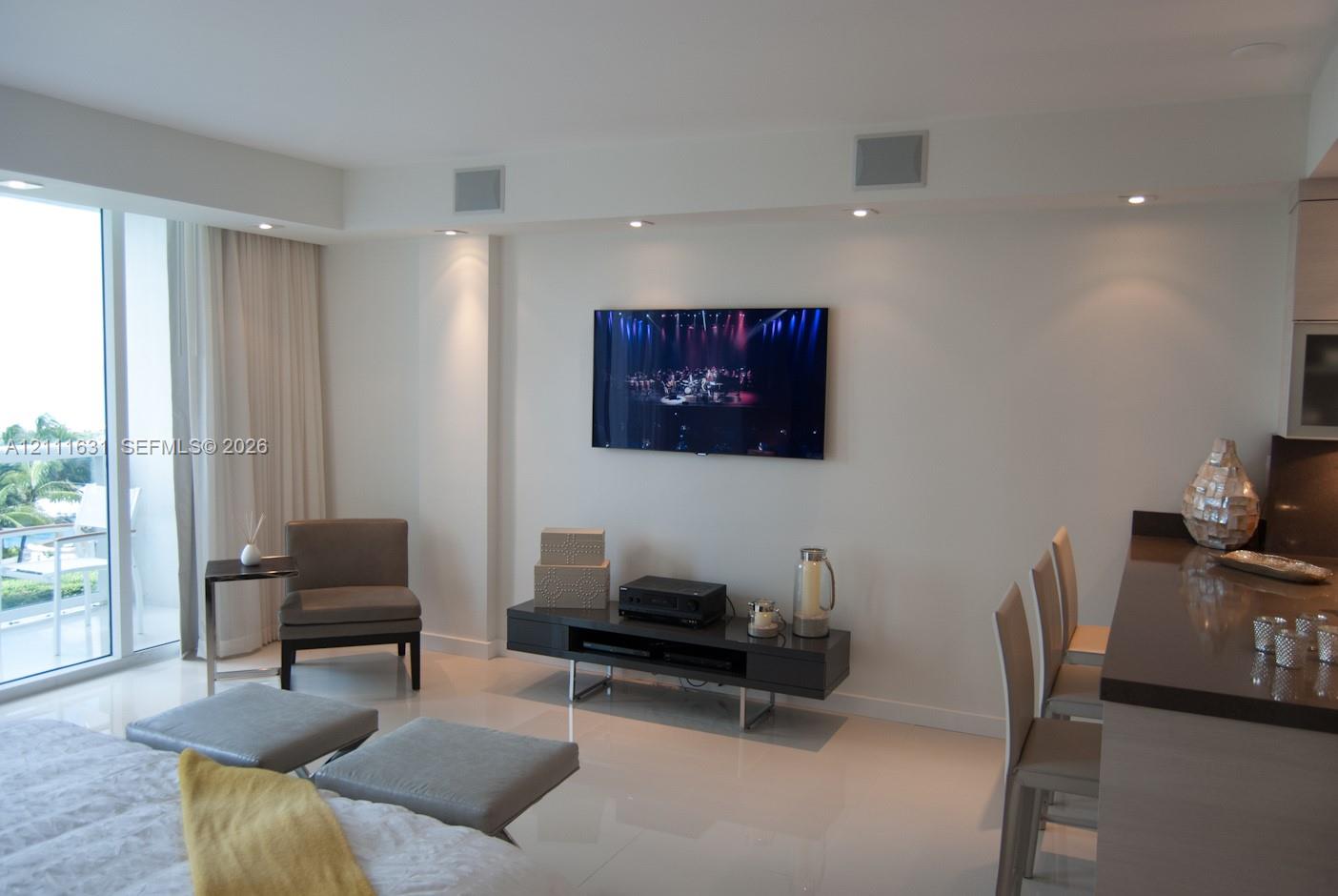Open-concept interior featuring large-format tile flooring, recessed ceiling lighting, and floor-to-ceiling glass sliding doors