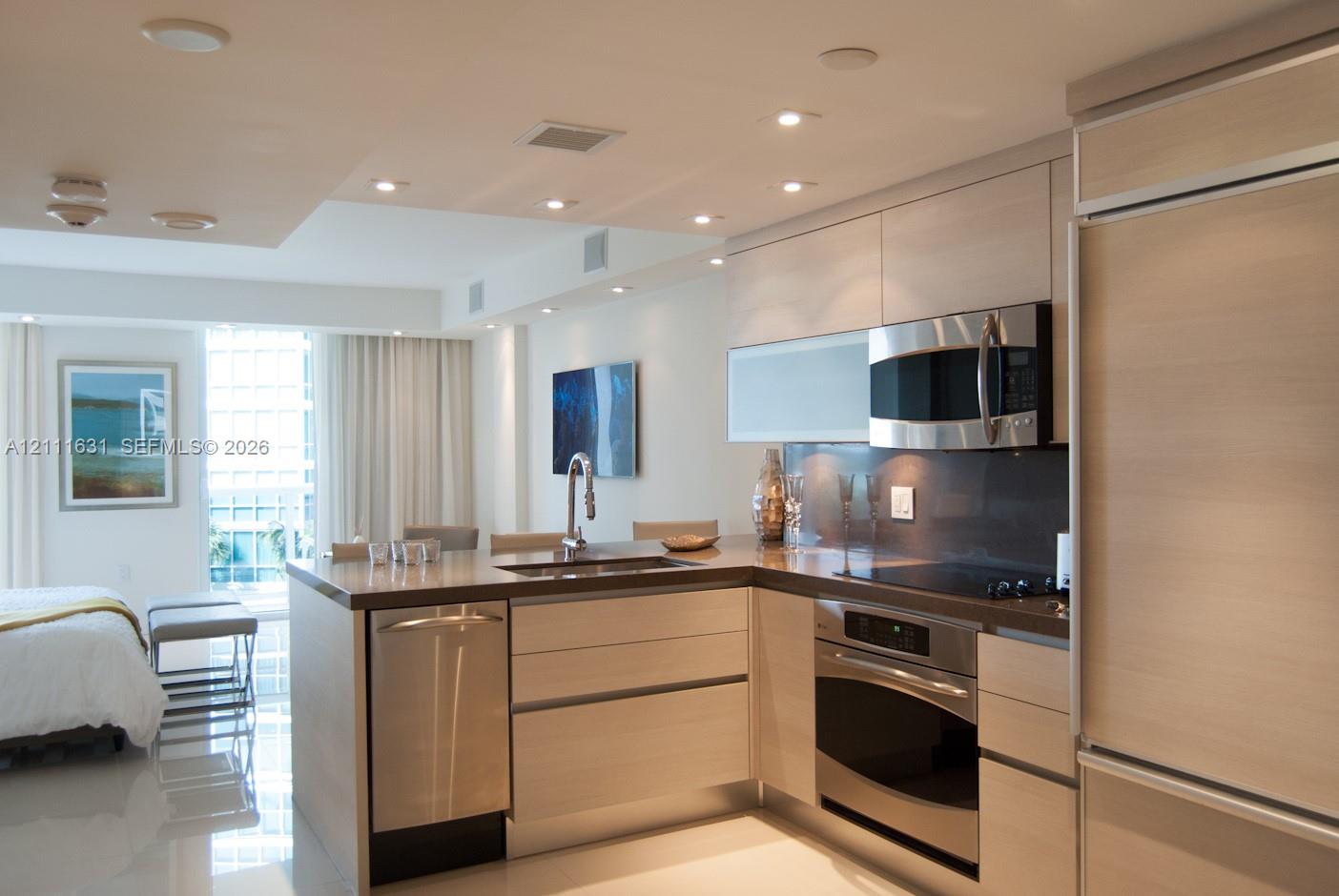Kitchen featuring light-finish cabinetry, stainless steel appliances, integrated dishwasher, solid-surface countertops, and recessed ceiling lighting Kitchen featuring light-finish cabinetry, stainless steel appliances, integrated dishwasher, solid-surface countertops, and recessed ceiling lighting