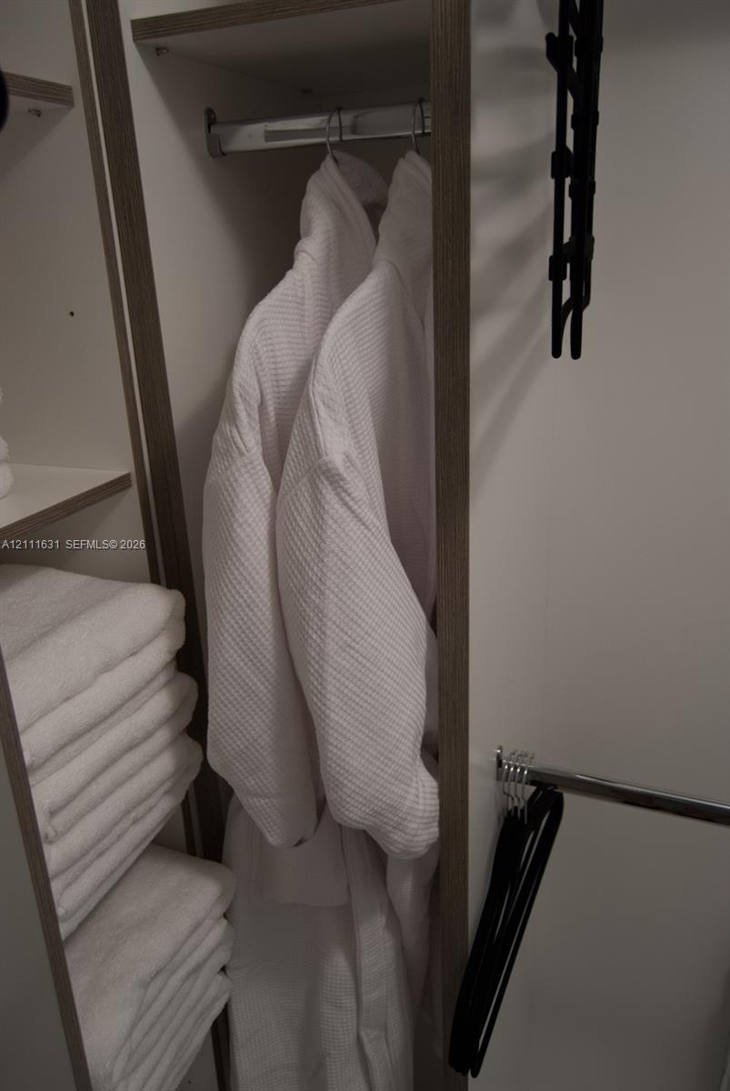 Built-in storage closet featuring wood-finish shelving and chrome hanging rods