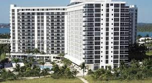 Multi-story high-rise building featuring private balconies, floor-to-ceiling windows, and ground-level pool area