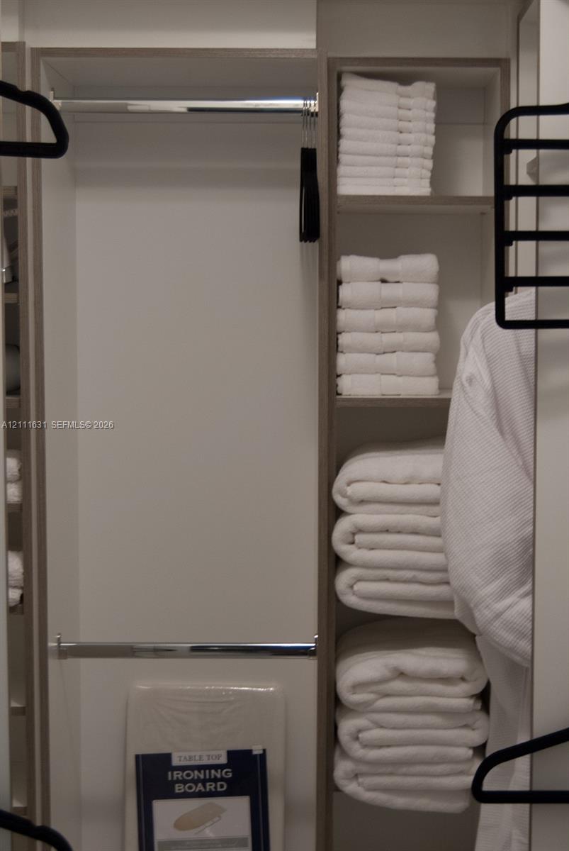 Custom reach-in closet featuring built-in vertical shelving, dual chrome hanging rods, and neutral-toned cabinetry finishes