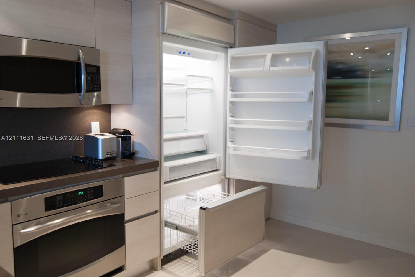Kitchen featuring custom integrated cabinetry, stainless steel oven, built-in microwave, and panel-ready refrigerator
