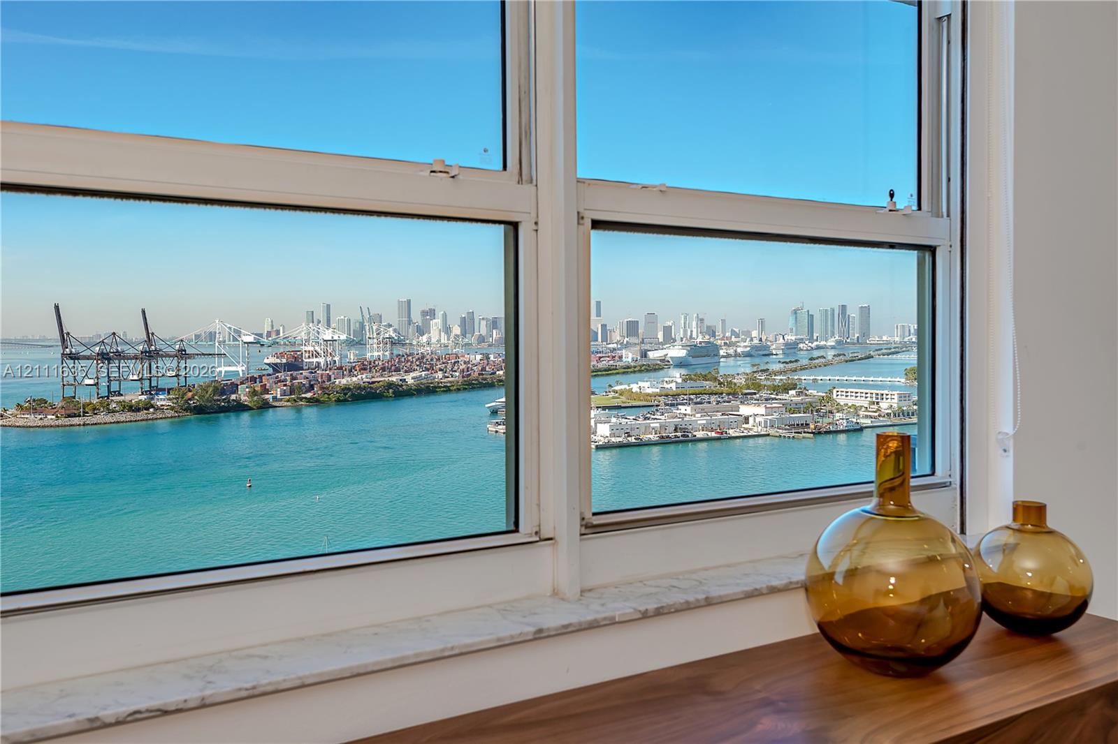 Large-pane windows with white framing and a stone sill overlooking the waterfront and cityscape