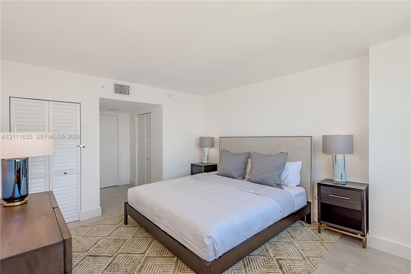 Bedroom featuring neutral wall finishes, tile flooring, and louvered closet doors