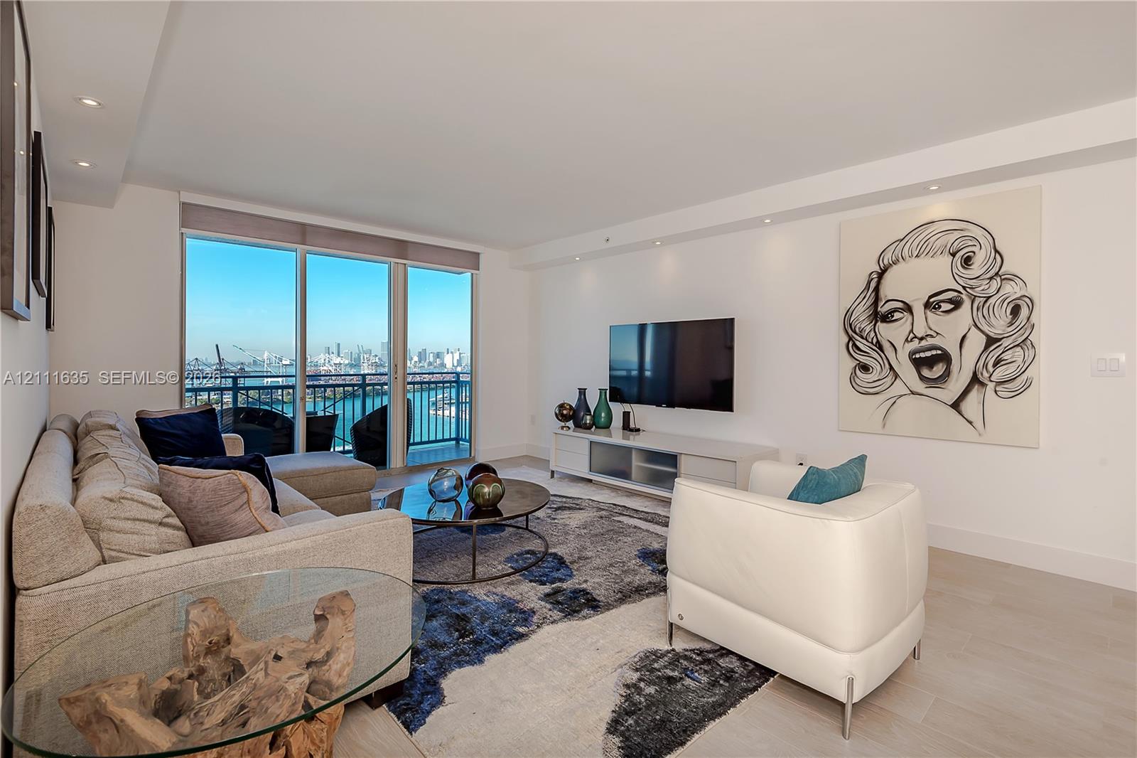 Open-concept room featuring floor-to-ceiling windows, light-toned wood-finish flooring, recessed lighting, and a private balcony