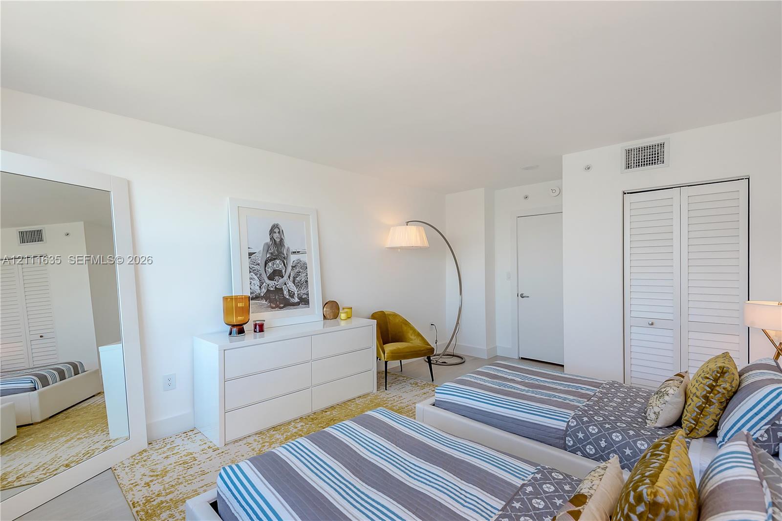 Neutral interior space featuring white walls, smooth-finish ceiling, and double-door closet with louvered panels