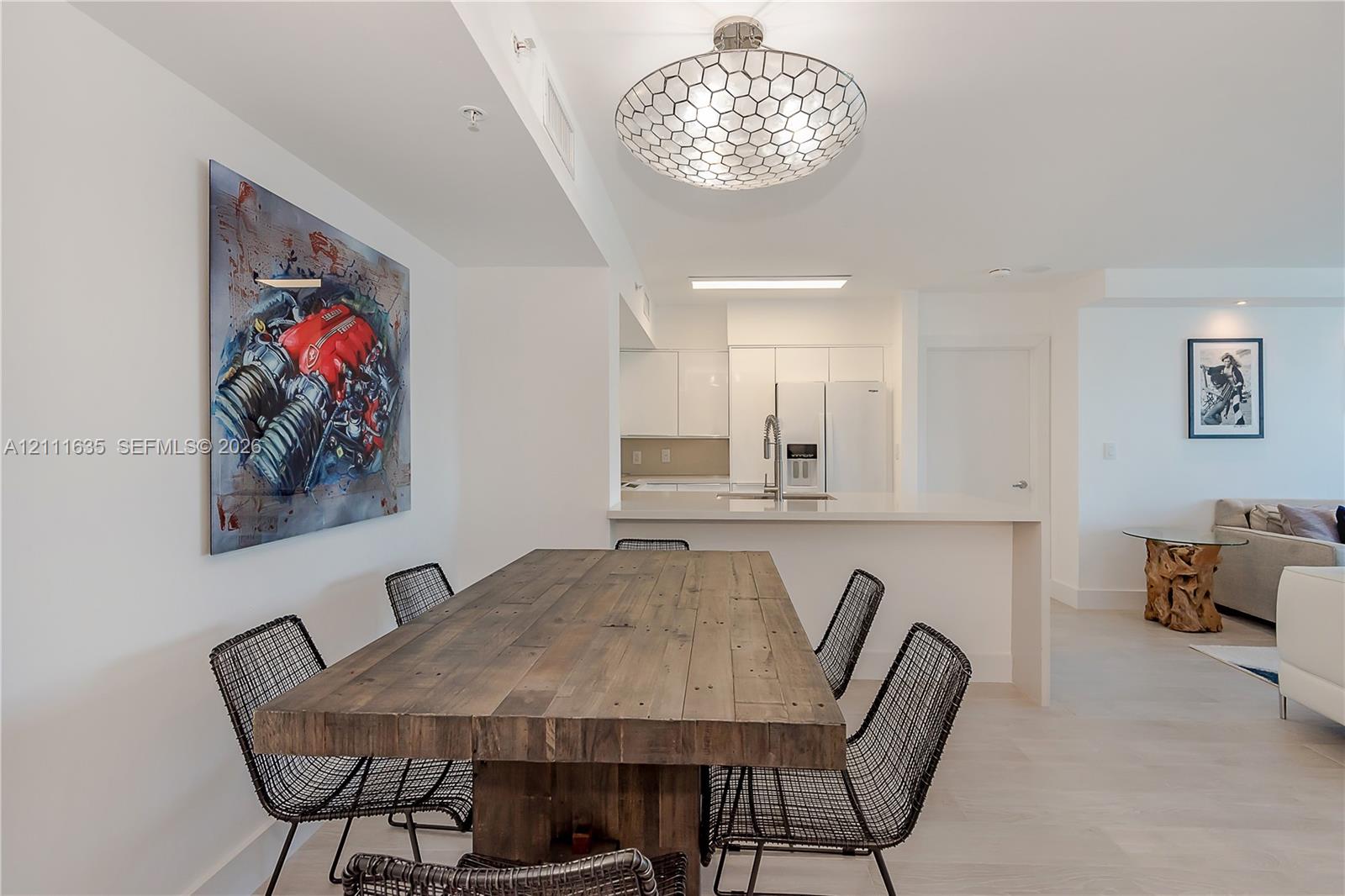Open-concept interior featuring light-toned flooring, geometric patterned ceiling fixture, and kitchen peninsula with integrated countertop