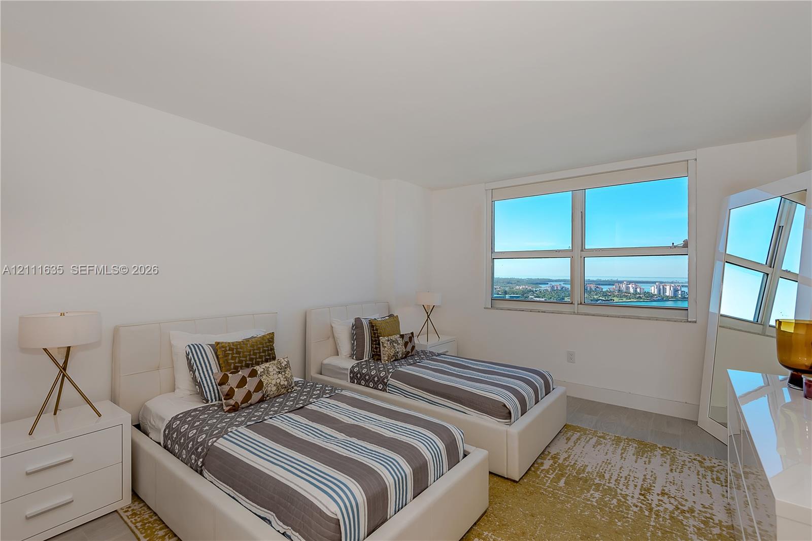 Large multi-pane window with water and coastal cityscape scenery, neutral wall finish, and tile flooring