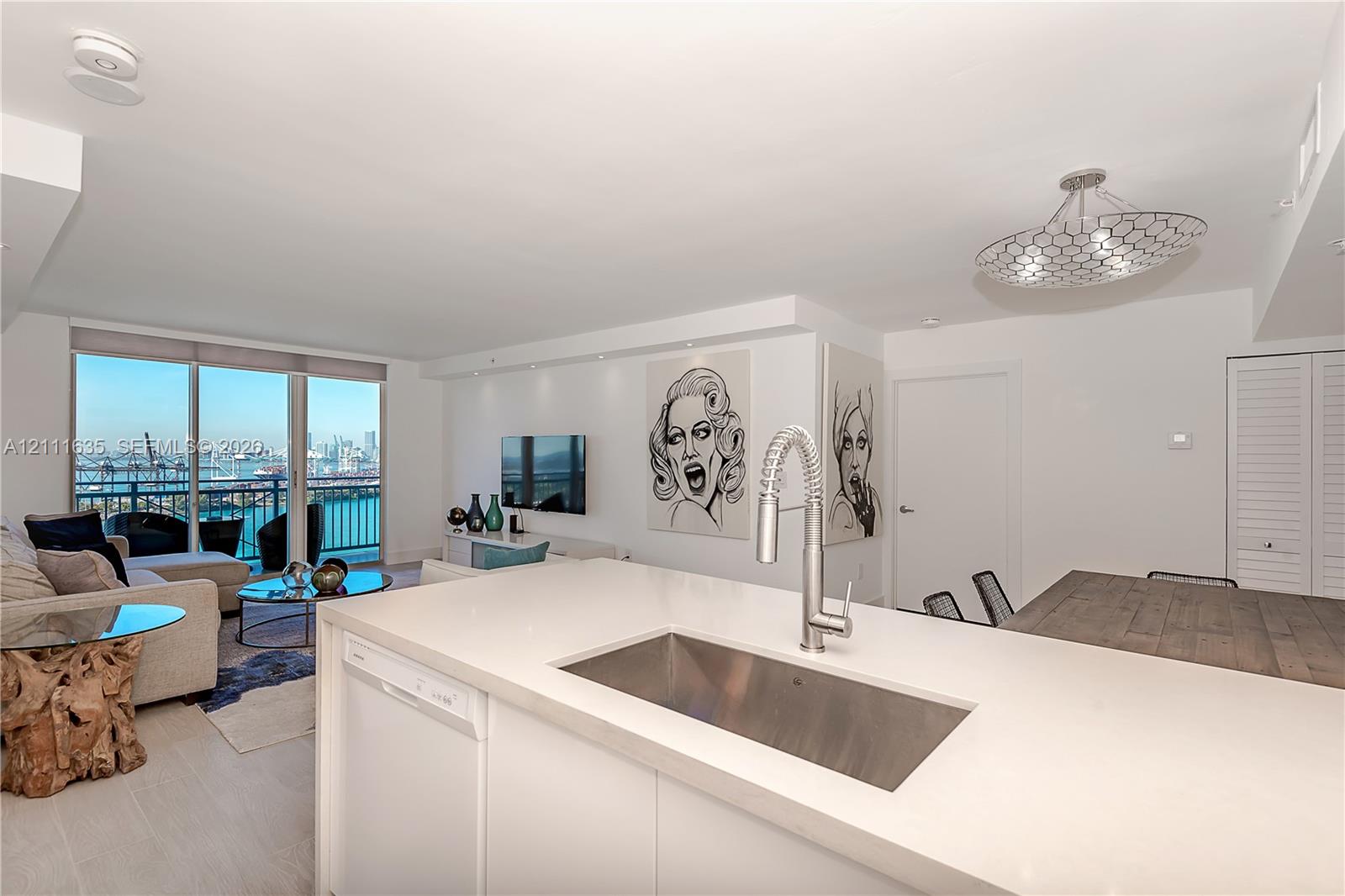 Kitchen featuring a white countertop with an integrated stainless steel rectangular sink and gooseneck faucet, floor-to-ceiling windows, and a decorative geometric ceiling fixture