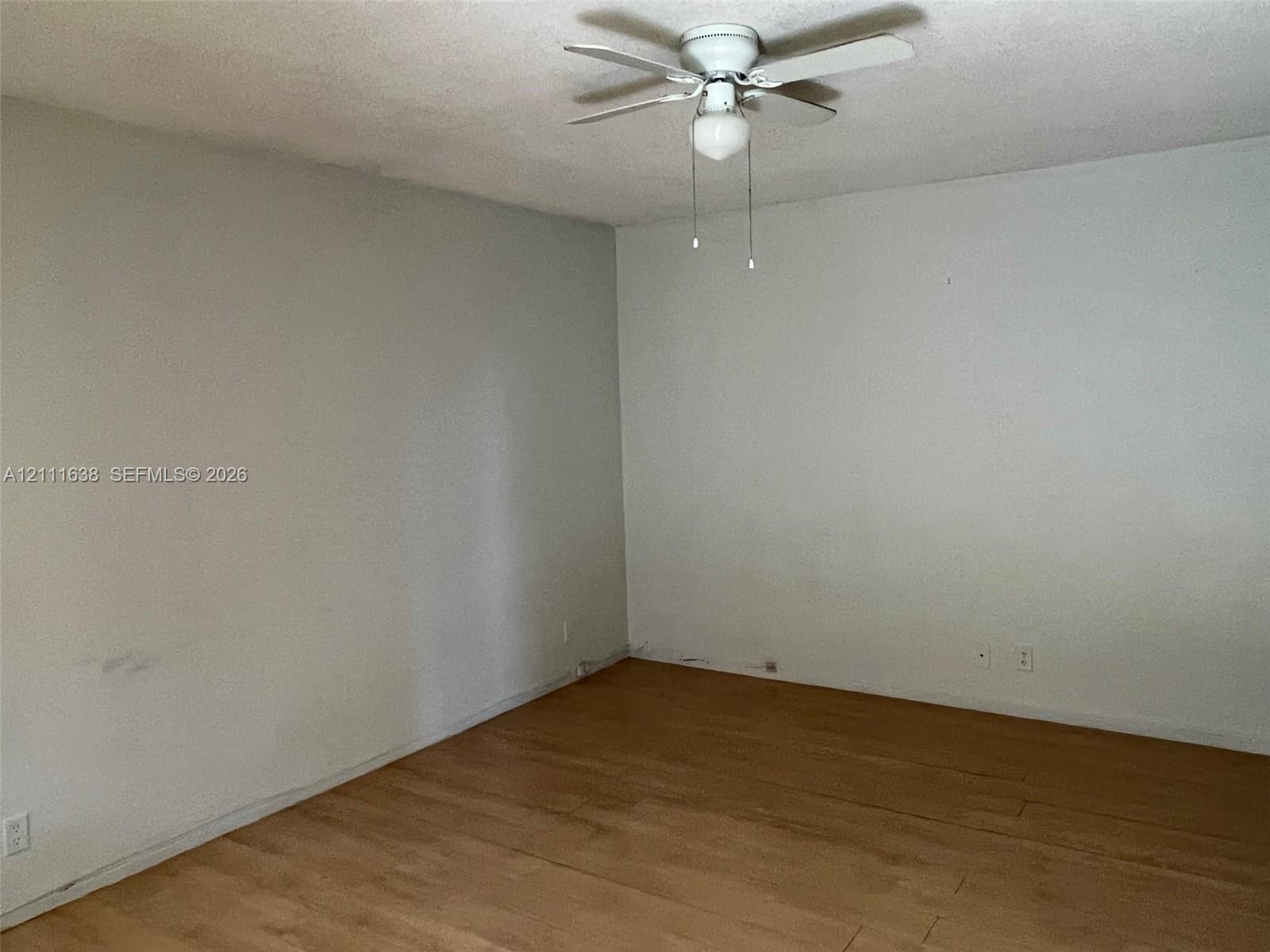 Interior space featuring wood-finish flooring and a ceiling fan with integrated light fixture