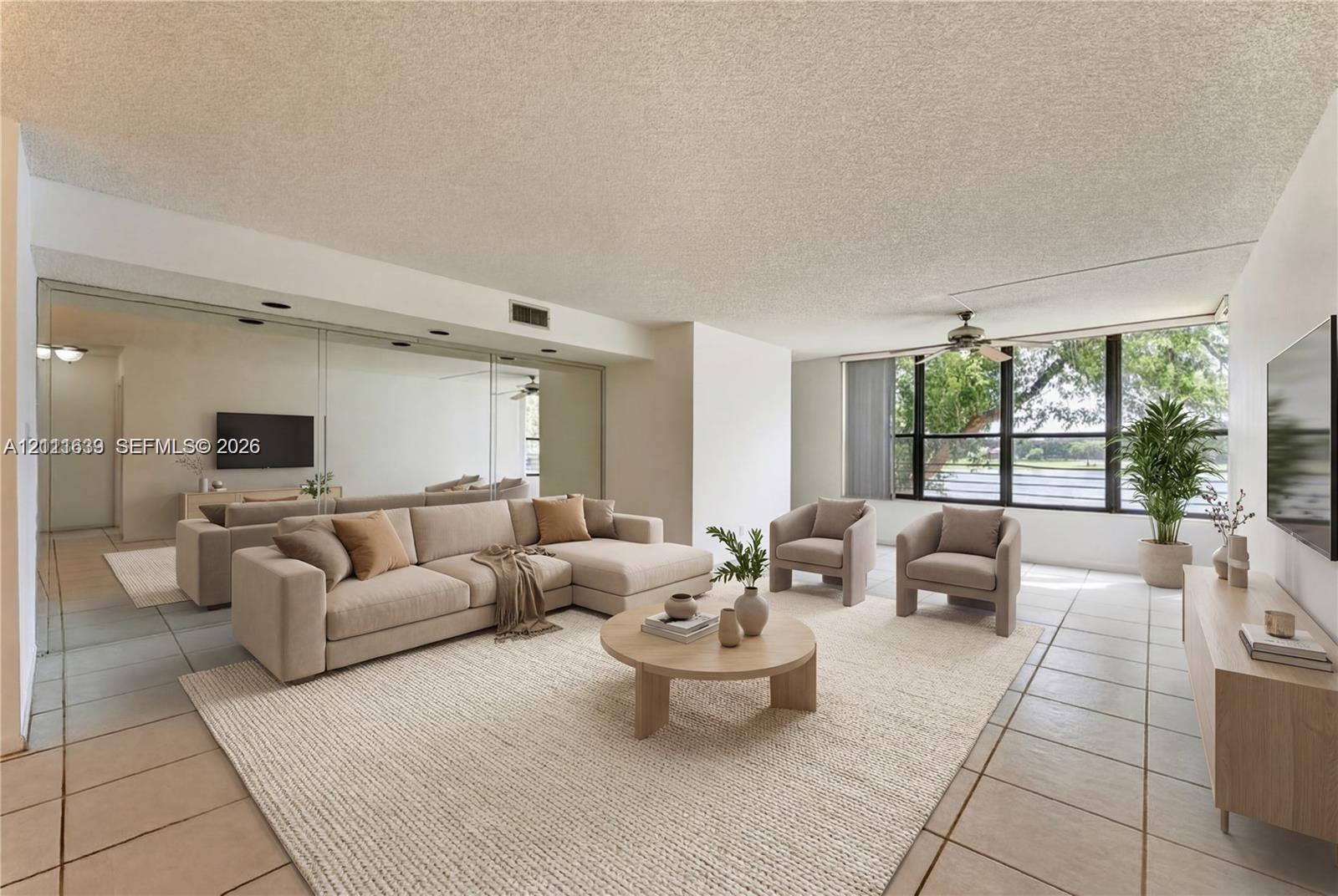 Open-concept living space featuring large-format ceramic tile flooring, floor-to-ceiling mirror paneling, a full-wall expanse of windows, and a ceiling-mounted fan Open-concept living space featuring large-format ceramic tile flooring, floor-to-ceiling mirror paneling, a full-wall expanse of windows, and a ceiling-mounted fan