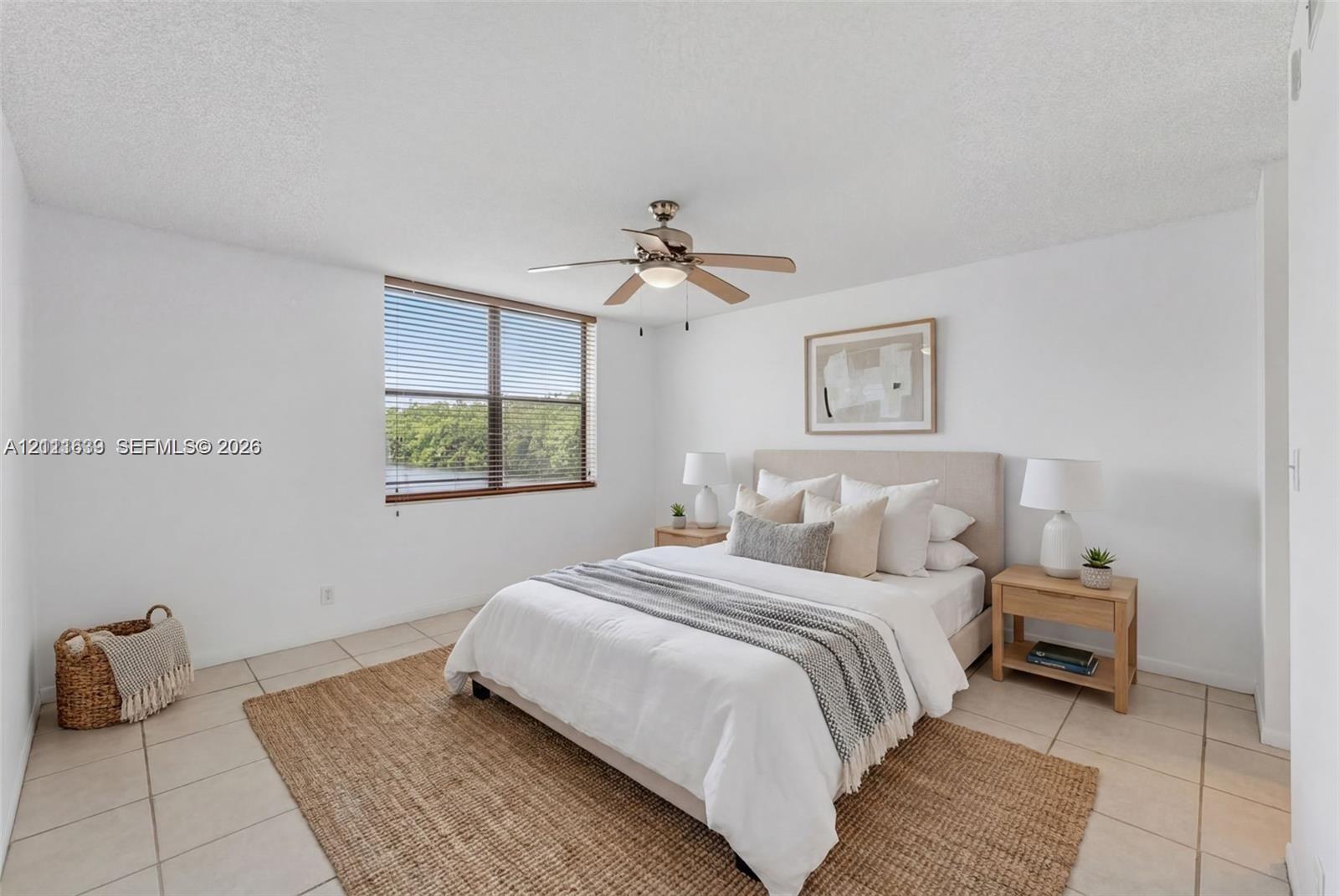 Neutral-toned tile flooring, large window with natural lighting, and ceiling-mounted light fixture with fan Neutral-toned tile flooring, large window with natural lighting, and ceiling-mounted light fixture with fan