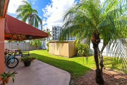 Covered concrete patio, fenced backyard, and mature palm trees