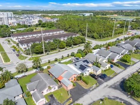 Aerial perspective of a suburban neighborhood featuring single-story residences with pitched roofs, integrated solar panels, asphalt driveways, and manicured lawn areas