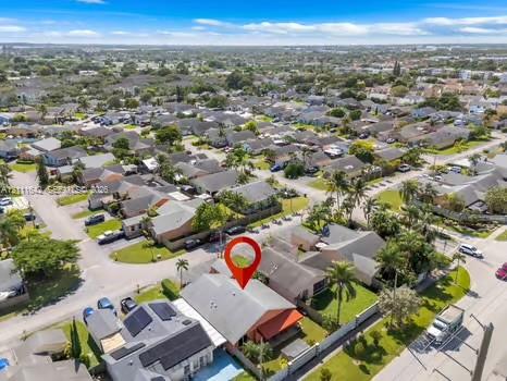 Aerial perspective featuring a single-story residence with a pitched roof, integrated covered patio area, and mature perimeter landscaping
