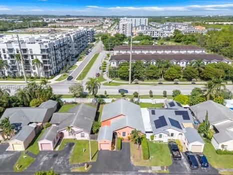 Aerial perspective of residential lots featuring asphalt driveways, attached single-car garages, hip-style roofing, and integrated solar panel systems