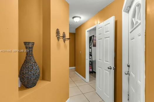 Entryway featuring recessed wall niche, ceramic tile flooring, six-panel interior door, and flush-mount ceiling lighting