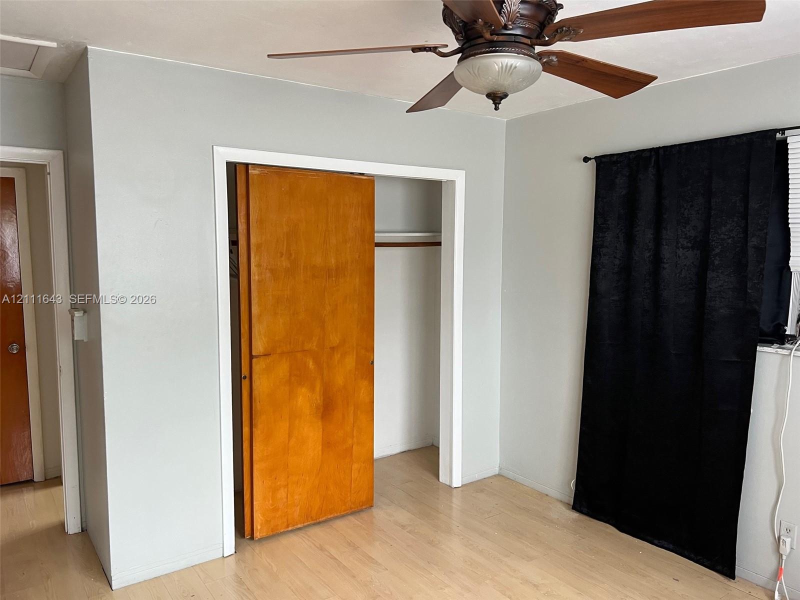 Wood-finish flooring, ceiling fan with integrated lighting, and natural wood closet door