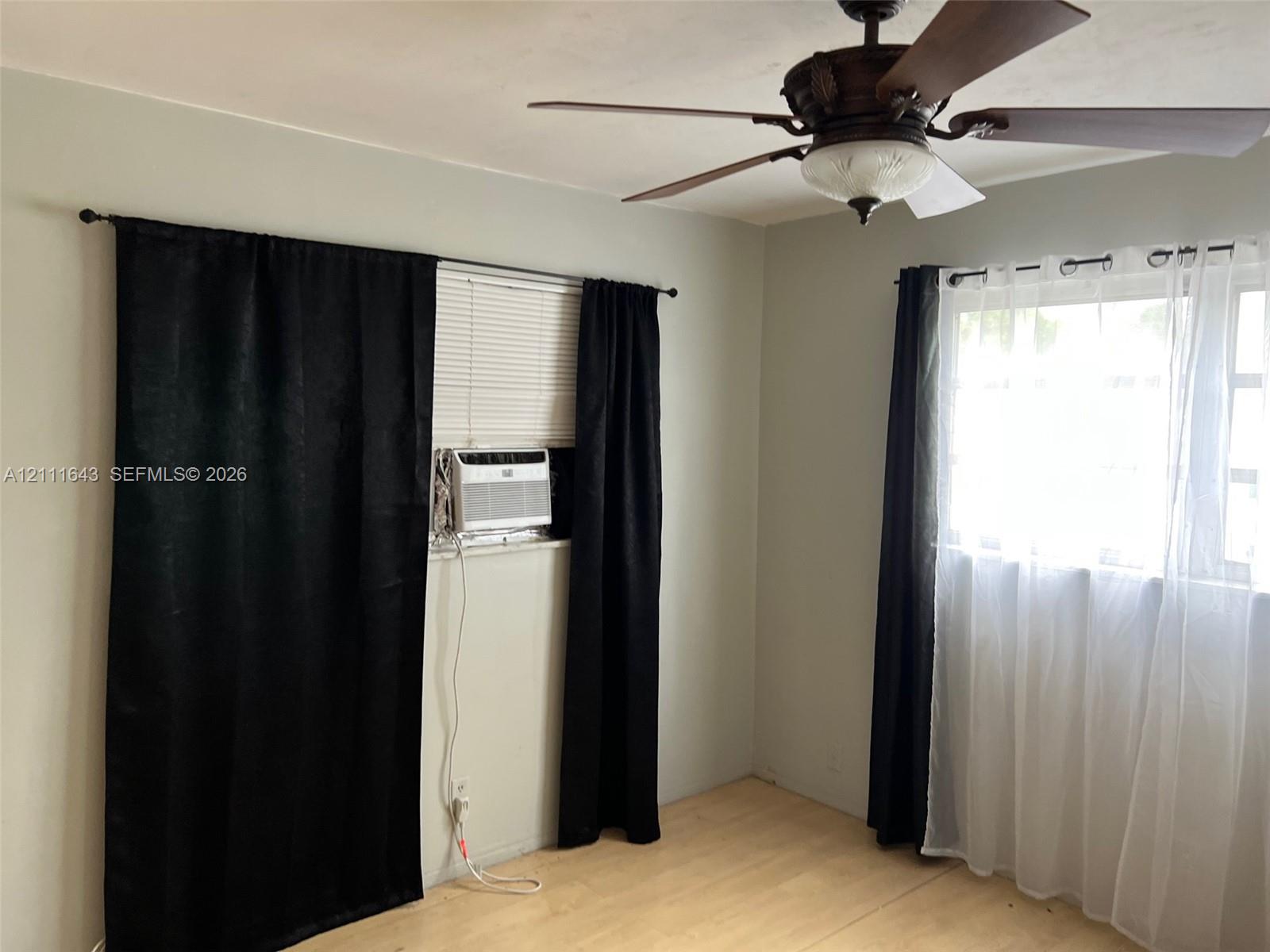 Light-toned wood-finish flooring, multi-pane windows, and a ceiling fan with integrated light fixture