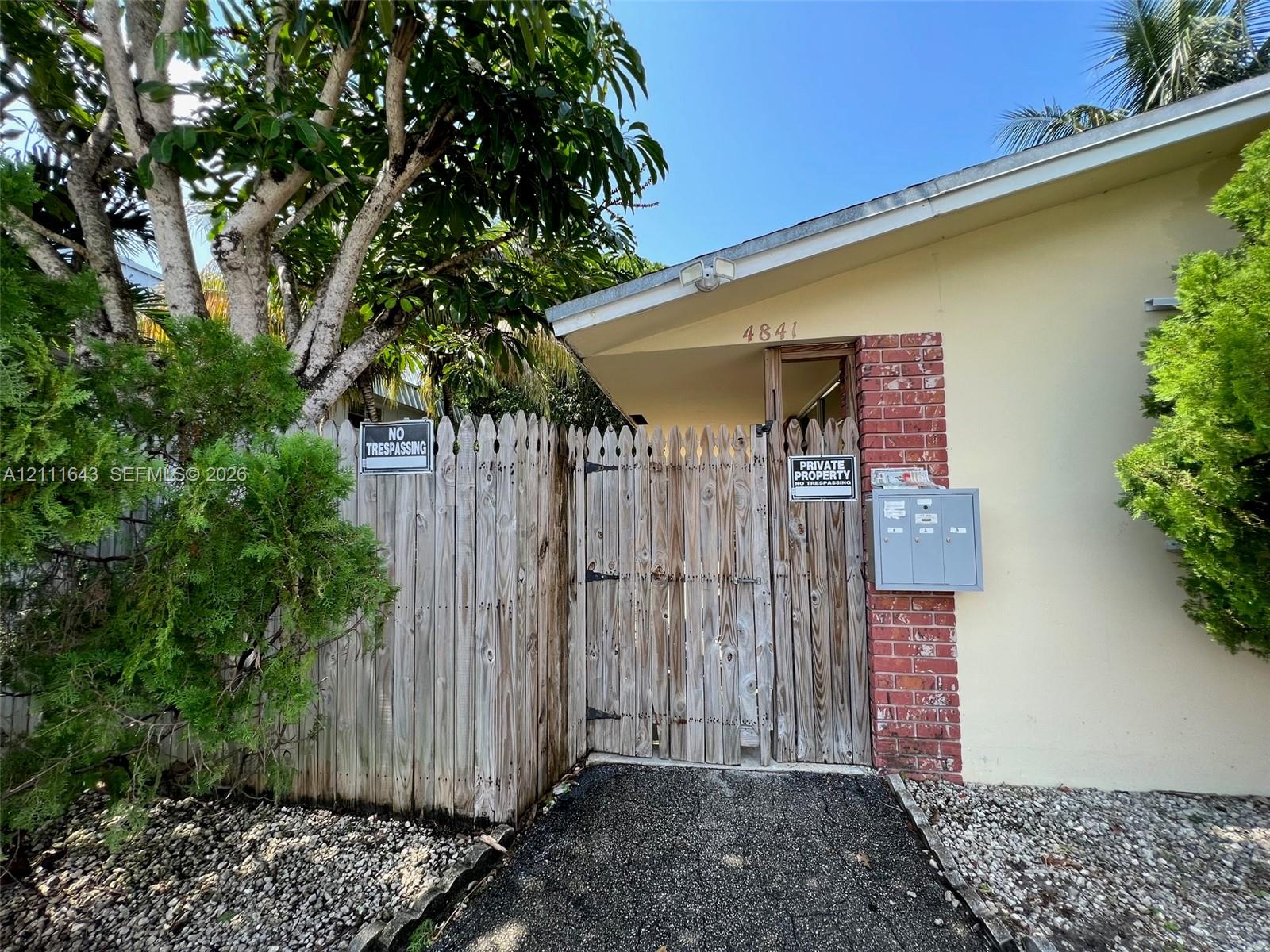 Exterior facade featuring brick masonry accents, a wooden privacy fence, and integrated mail collection receptacles